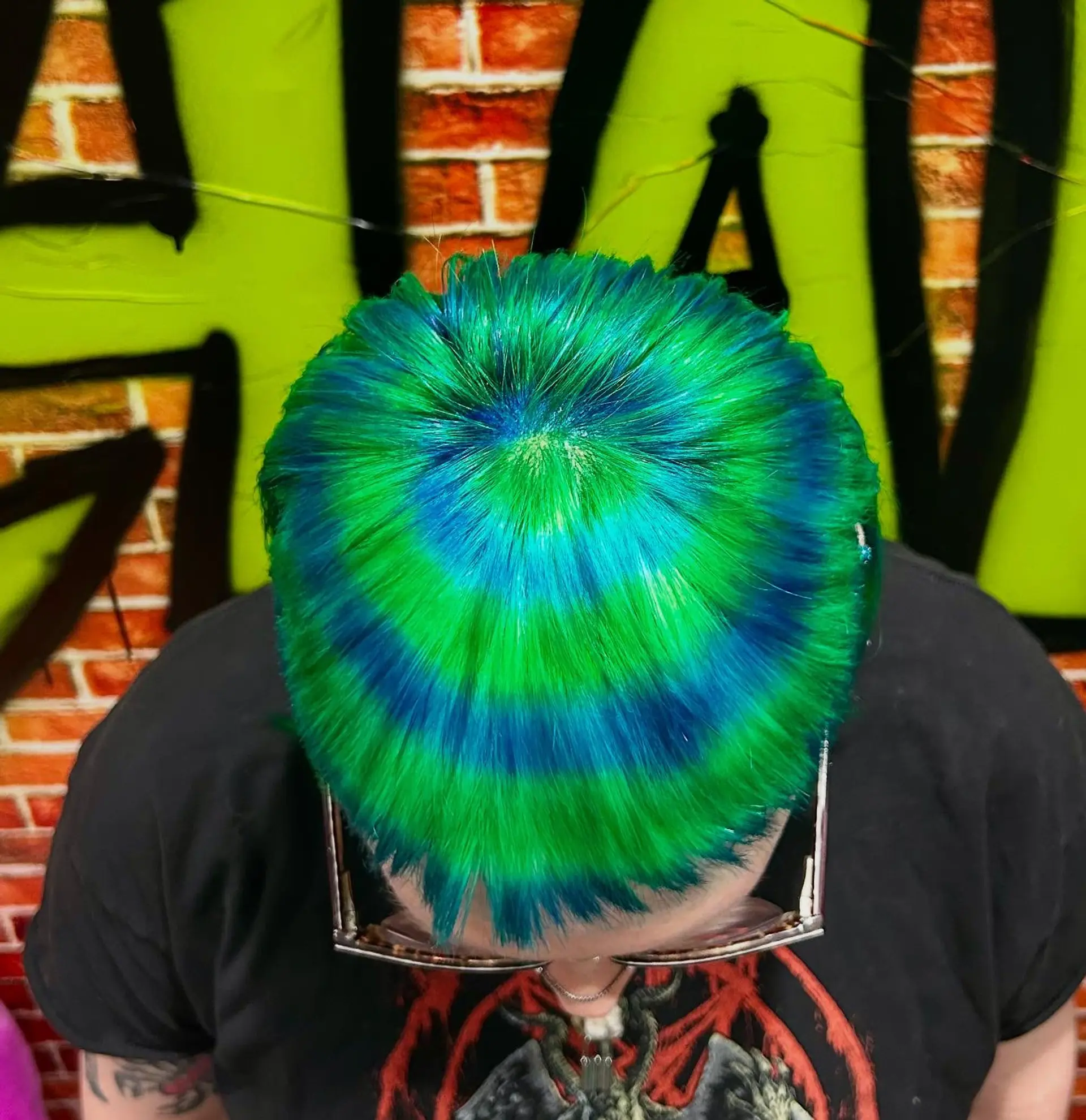 A short crop dyed in hypnotic concentric circles of vibrant neon green, cyan, and deep blue radiating from the crown. 1