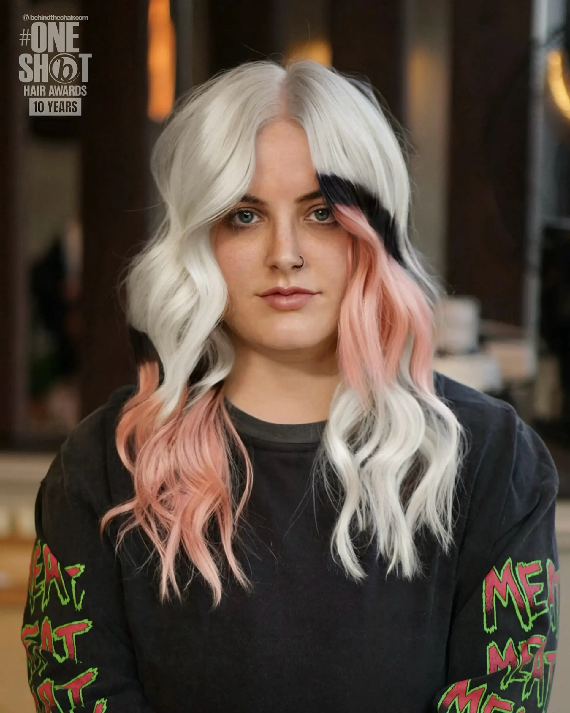 Medium-length wavy platinum blonde hair styled with a center part and bold color-blocked sections in black and soft pink. 1