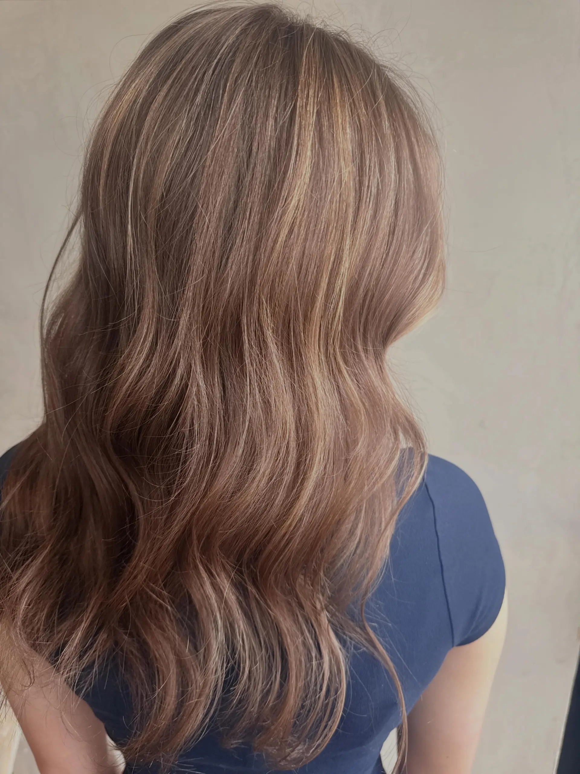 Long light brown hair styled in soft, loose waves featuring subtle, sun-kissed blonde highlights throughout. 1