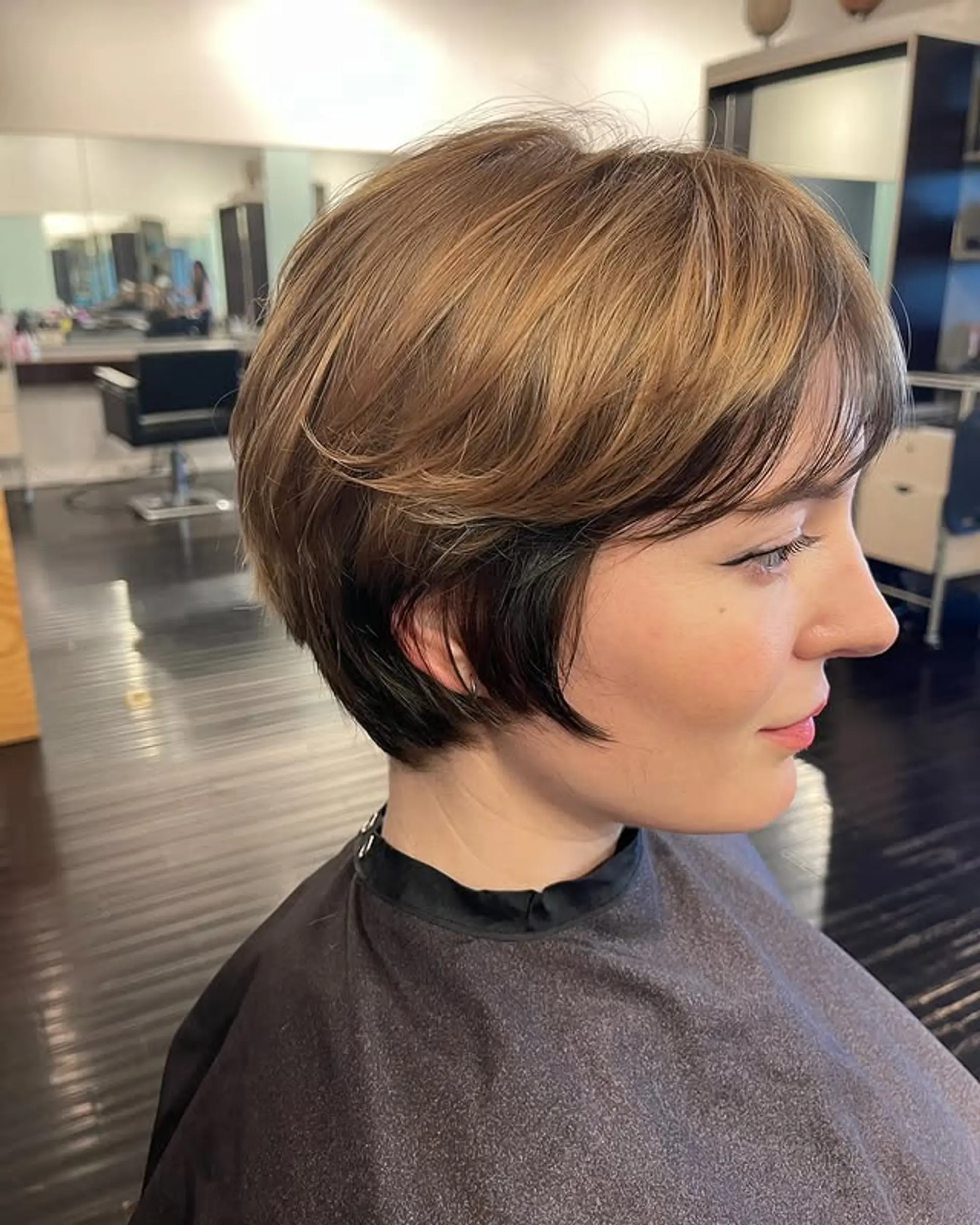 A short, layered pixie cut with a textured finish and 'bronde' highlights. 1