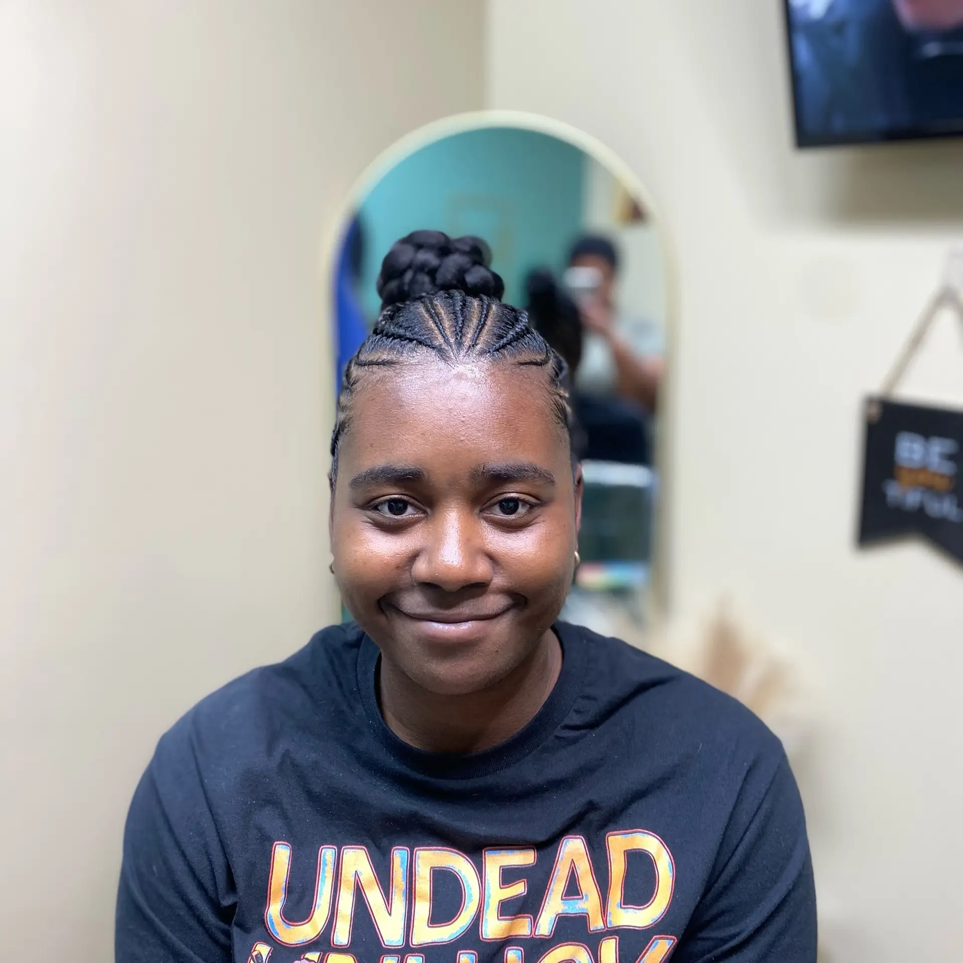 Neat cornrows feed upward into a sleek, voluminous braided high bun. 1