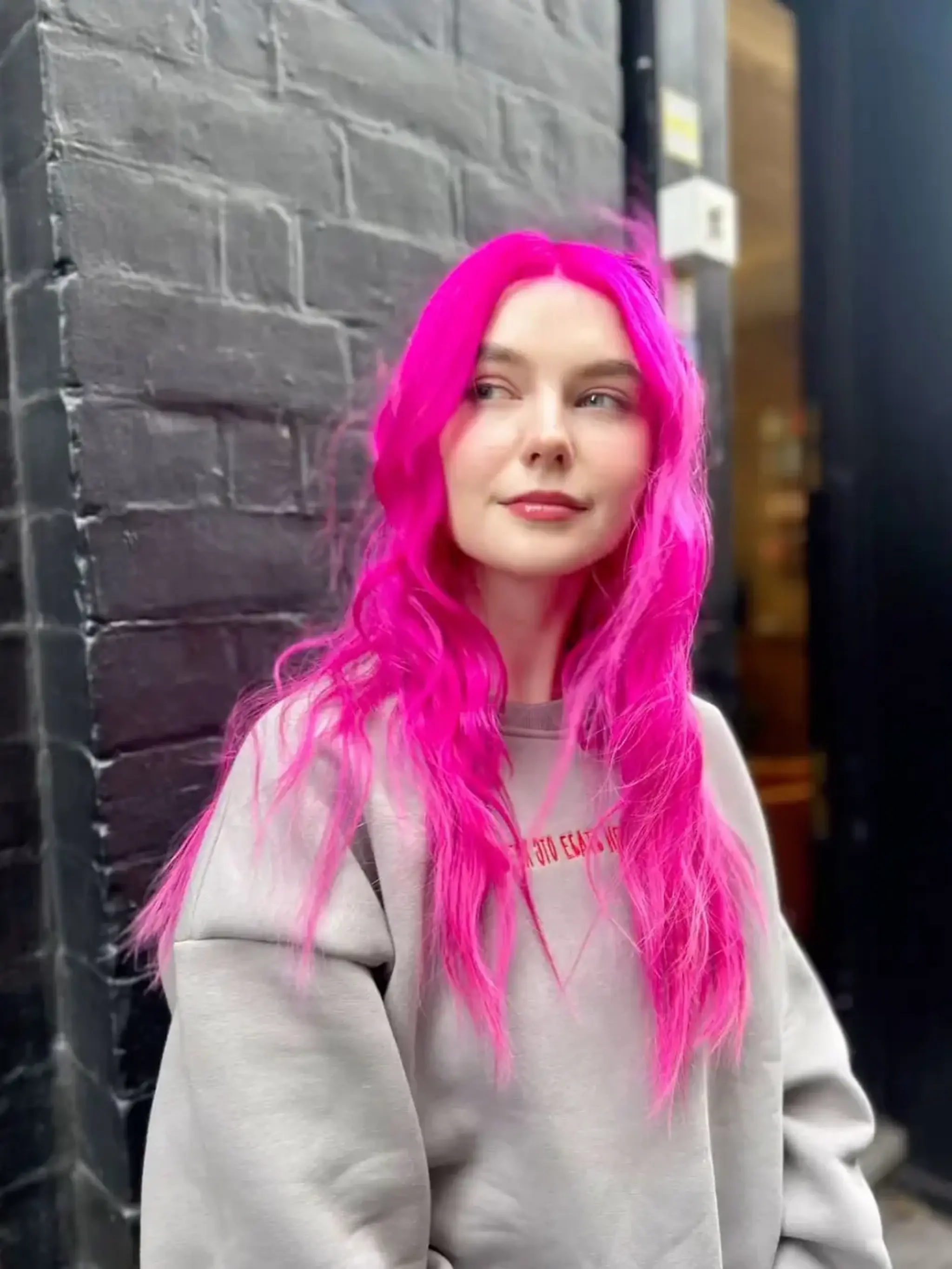 Long, wavy hair in a bright neon pink color, parted center with loose waves giving a playful and youthful look.