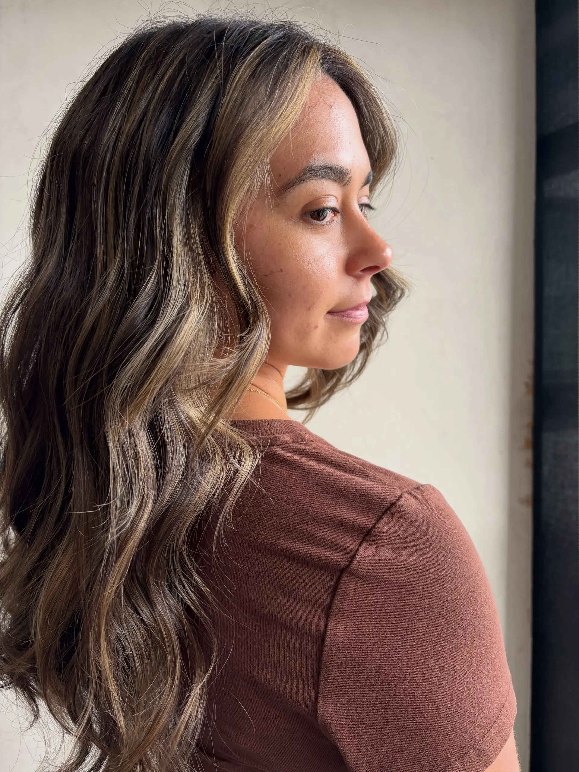 Long wavy brunette hair featuring seamless dimensional balayage highlights with brighter face-framing strands. 1
