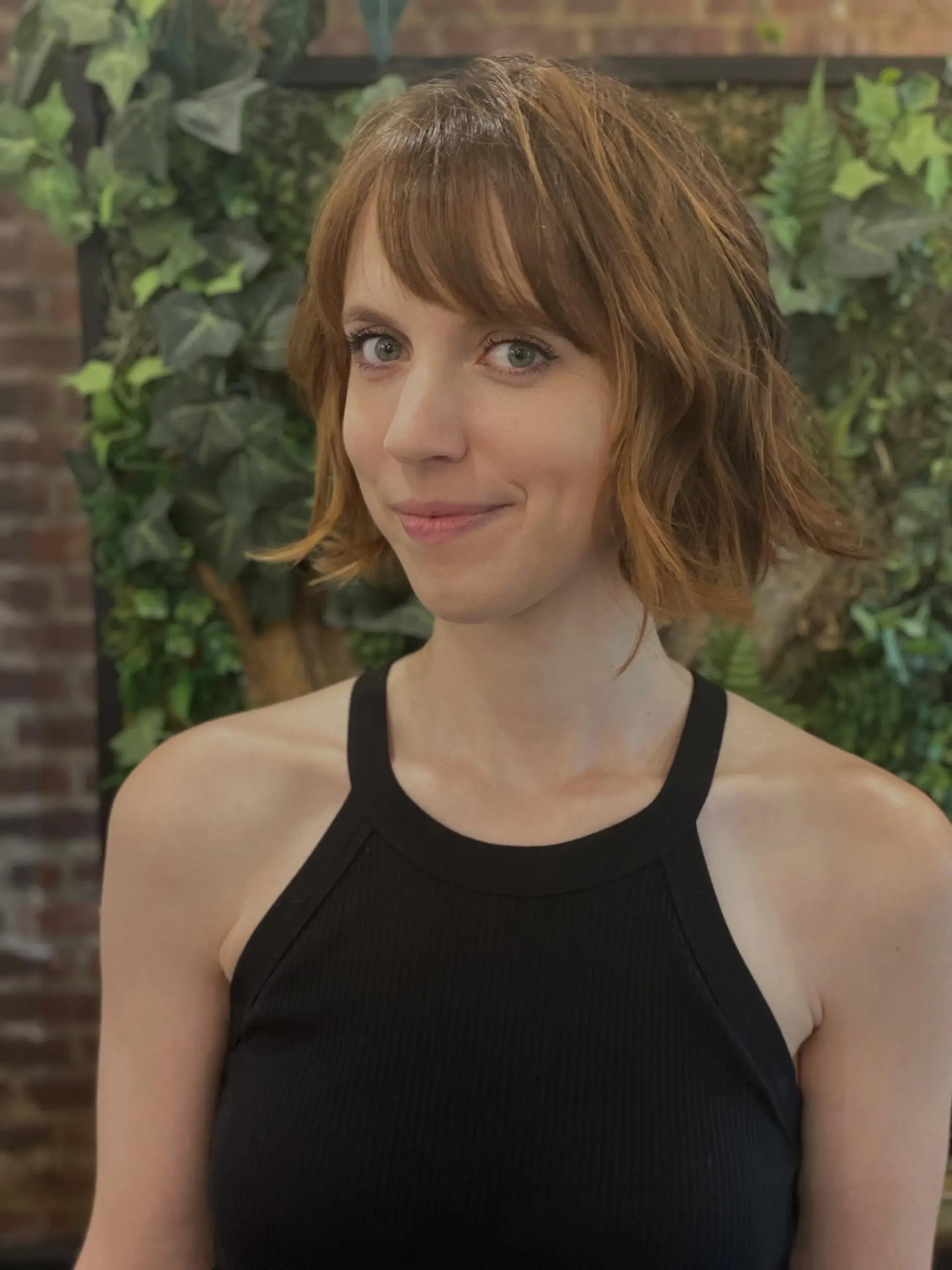 A chin-length textured wavy bob with wispy bangs and warm golden copper tones. Current Cut My Hair service: $215 for haircut and included finish only; displayed color is not included. 1
