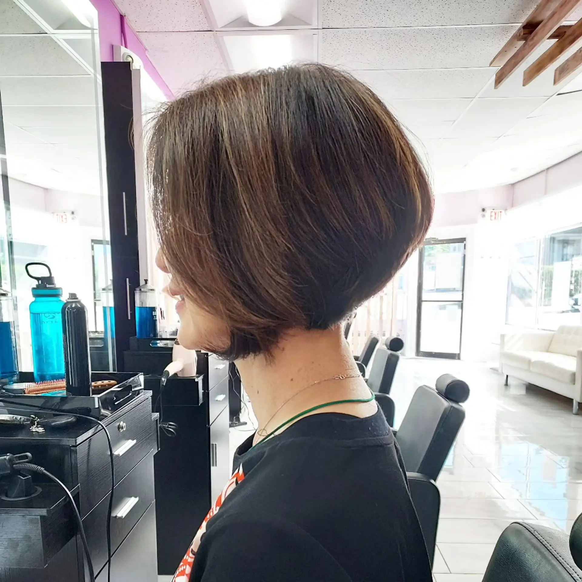 A sleek short stacked bob haircut with subtle warm brown tones, featuring a clean, curved silhouette with volume at the crown. 1