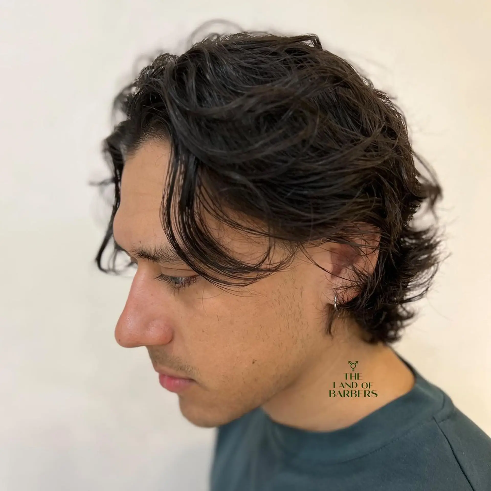 Medium length, wavy dark brown hair with a layered cut. Soft waves frame the face and sides are tucked behind the ears for a relaxed style. 1