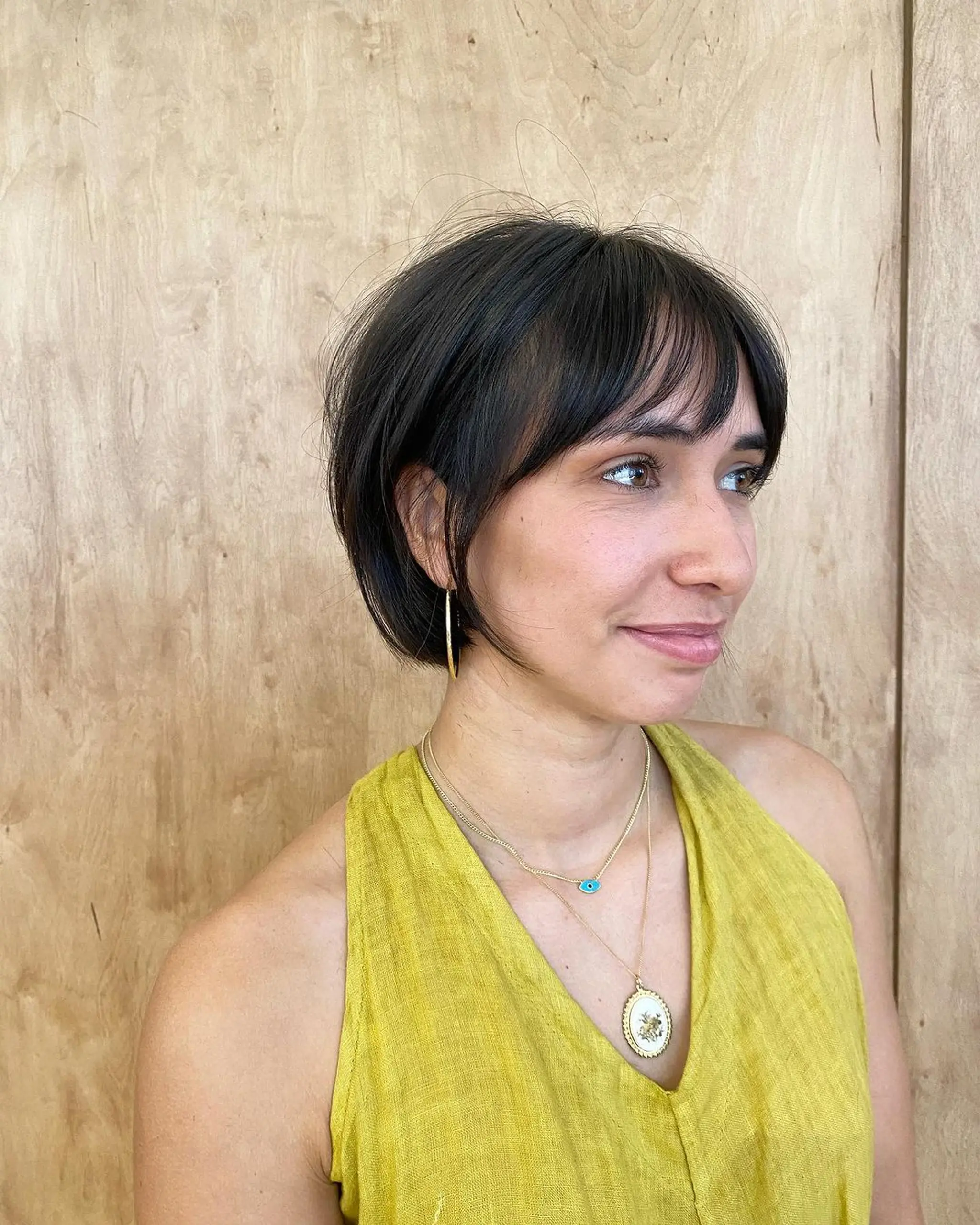 A chic tapered bob with dark brown and light brown highlights, featuring layers and a stylish fringe.