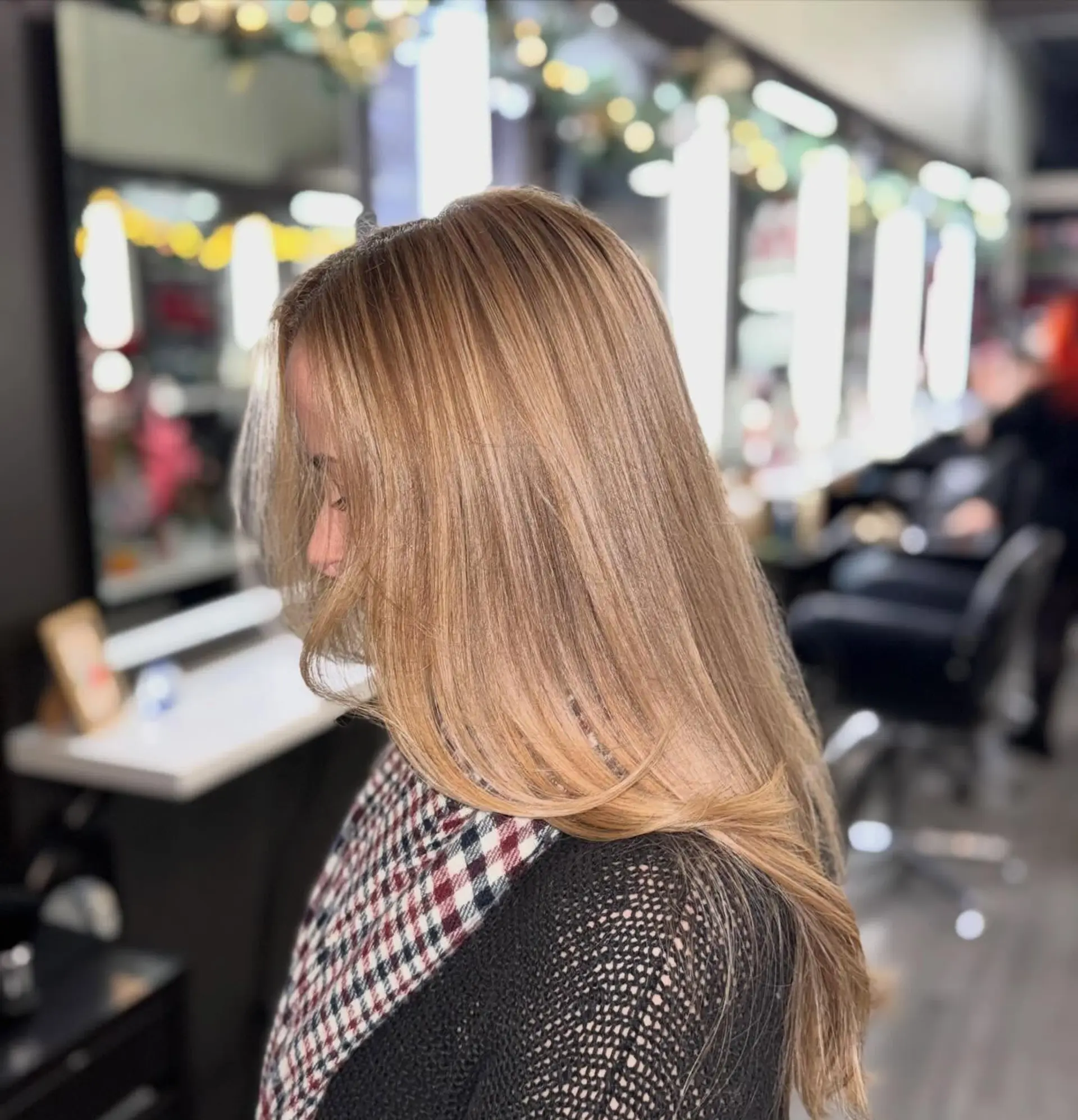 Long, smoothly blown-out hair featuring dimensional warm honey blonde highlights over a light brown base with subtle curved ends. 1