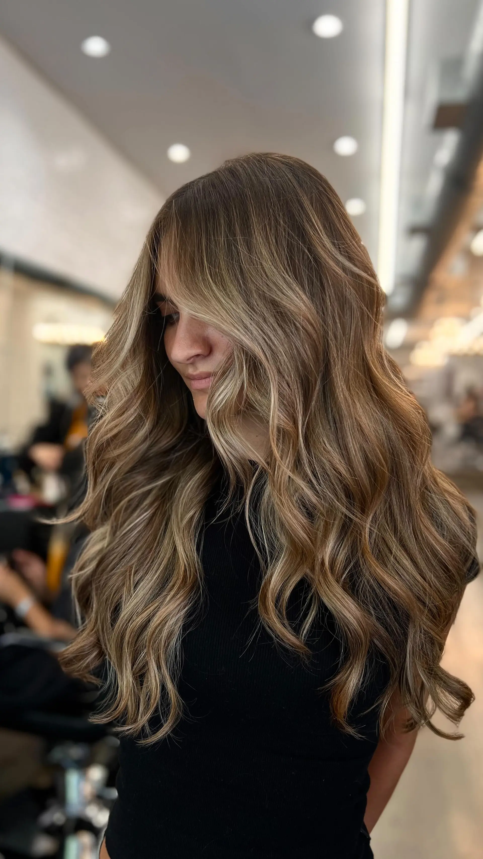 Long bronde hair featuring soft, dimensional balayage highlights styled in loose, voluminous waves. 1