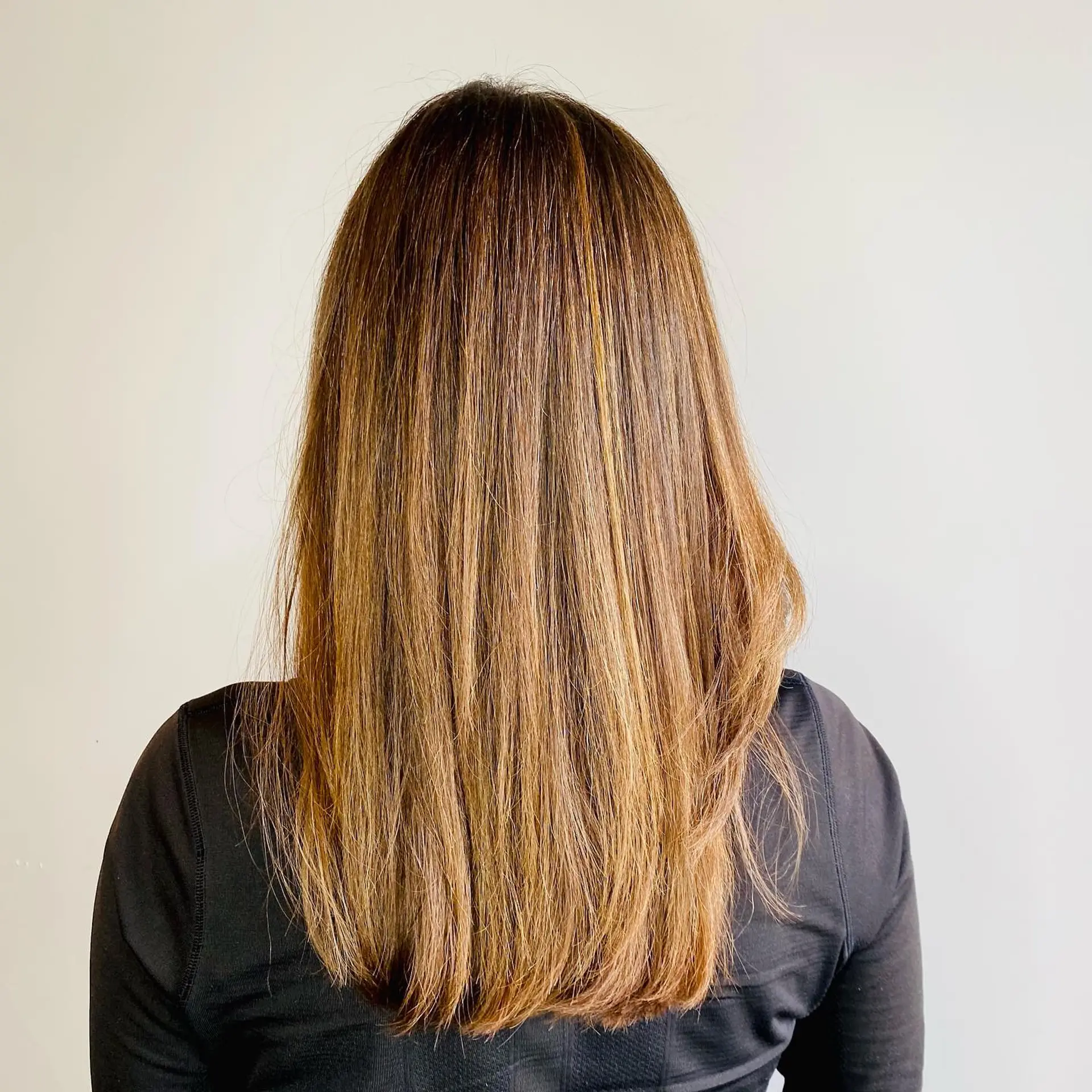 Straight, long brunette hair featuring finely woven golden babylights that add subtle dimension and radiance throughout. 1
