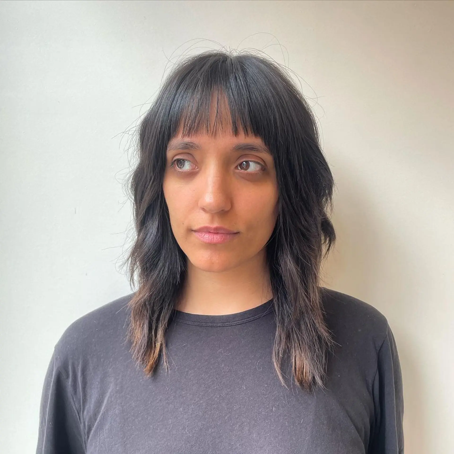 Medium-length wavy cut with a soft fringe and dark brown hair featuring light brown highlights, offering a layered texture. 1