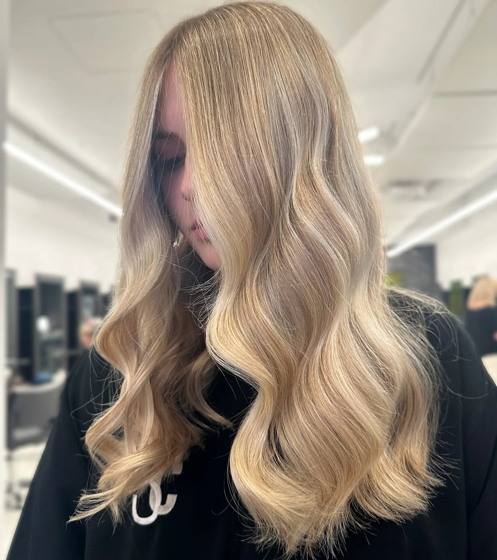 Long dimensional blonde hair styled in soft, cascading waves with a smooth blowout finish. 1