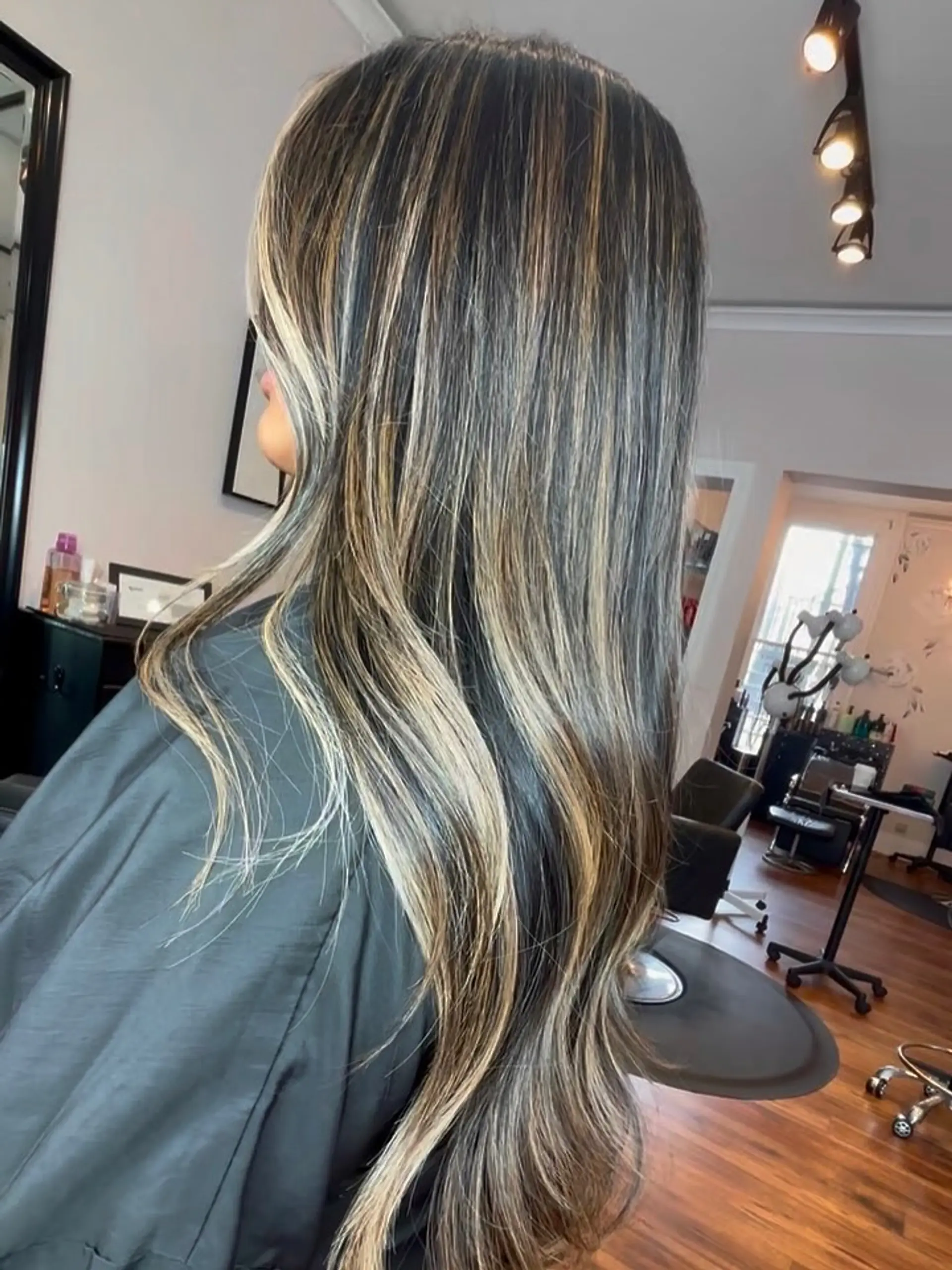 Long dark brown hair enhanced with blended blonde highlights and soft, subtle waves through the ends. 1