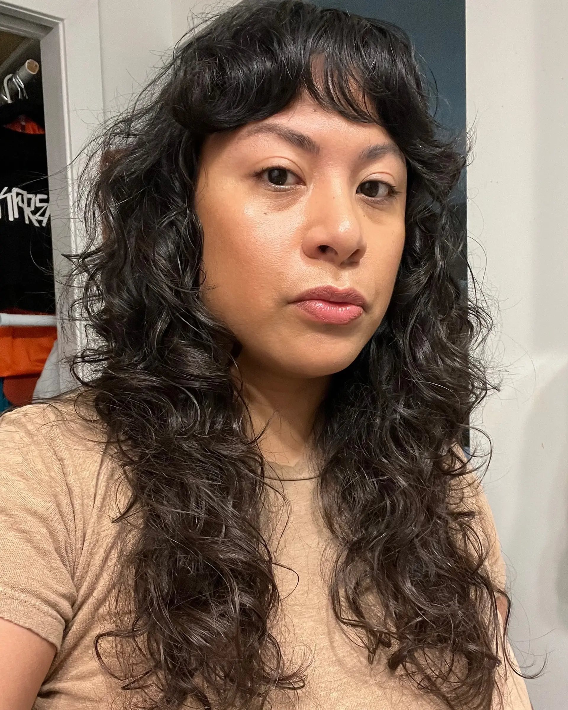 A long, textured curly shag haircut with soft, face-framing fringe bangs and defined waves. 1