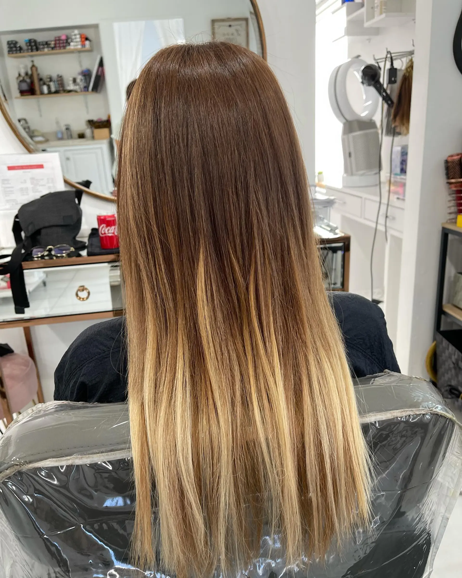 Long, sleek straight hair featuring a warm brown base seamlessly blending into bright honey blonde balayage ends. 1