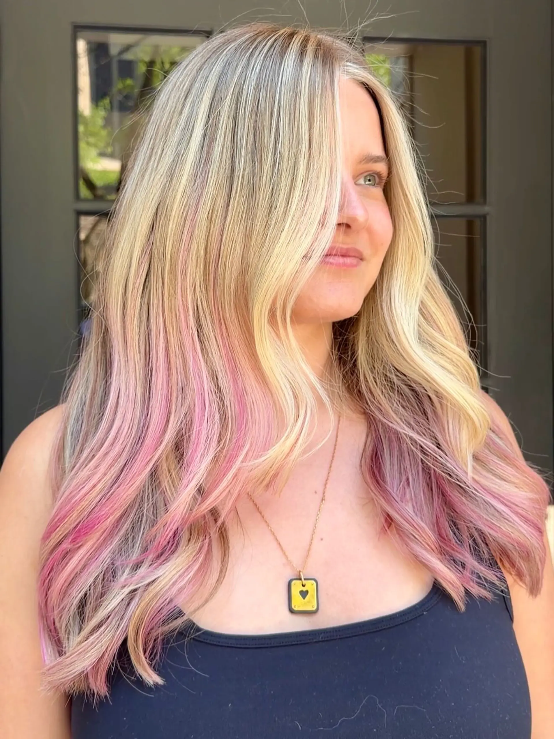 Long highlighted blonde hair featuring hidden pops of pink peekaboo color underneath, styled in soft waves. 1