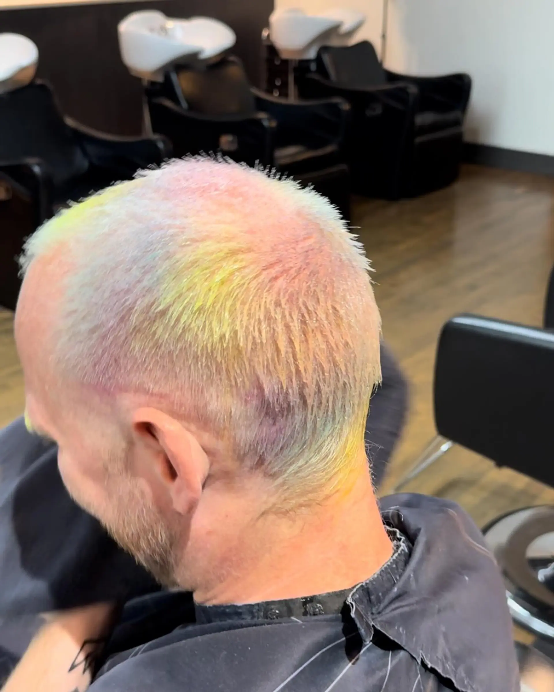 A very short buzz cut with a vibrant rainbow hair color effect. 2