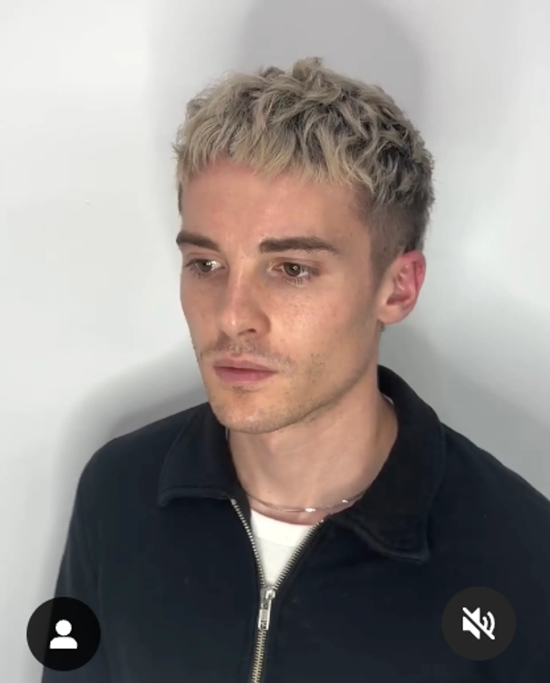 A short, wavy hairstyle with textured ash blonde tips and tapered sides, offering a modern and edgy look. 2