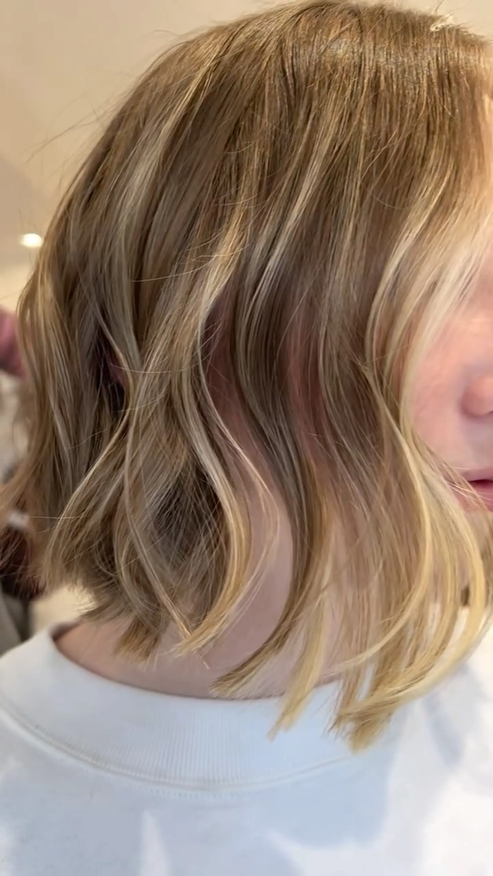 A chic, chin-length textured bob styled in soft, loose waves with dimensional blonde highlights. 1