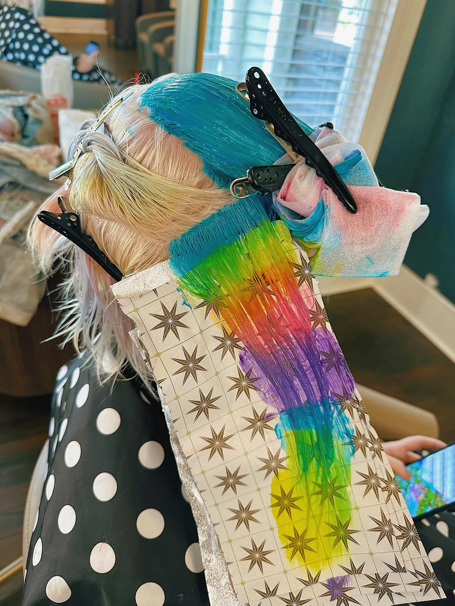 A short, blunt bob styled with a vibrant turquoise and teal main color, accented by hidden peek-a-boo panels of hot pink, purple, and yellow-green, creating a striking multi-dimensional effect. 3