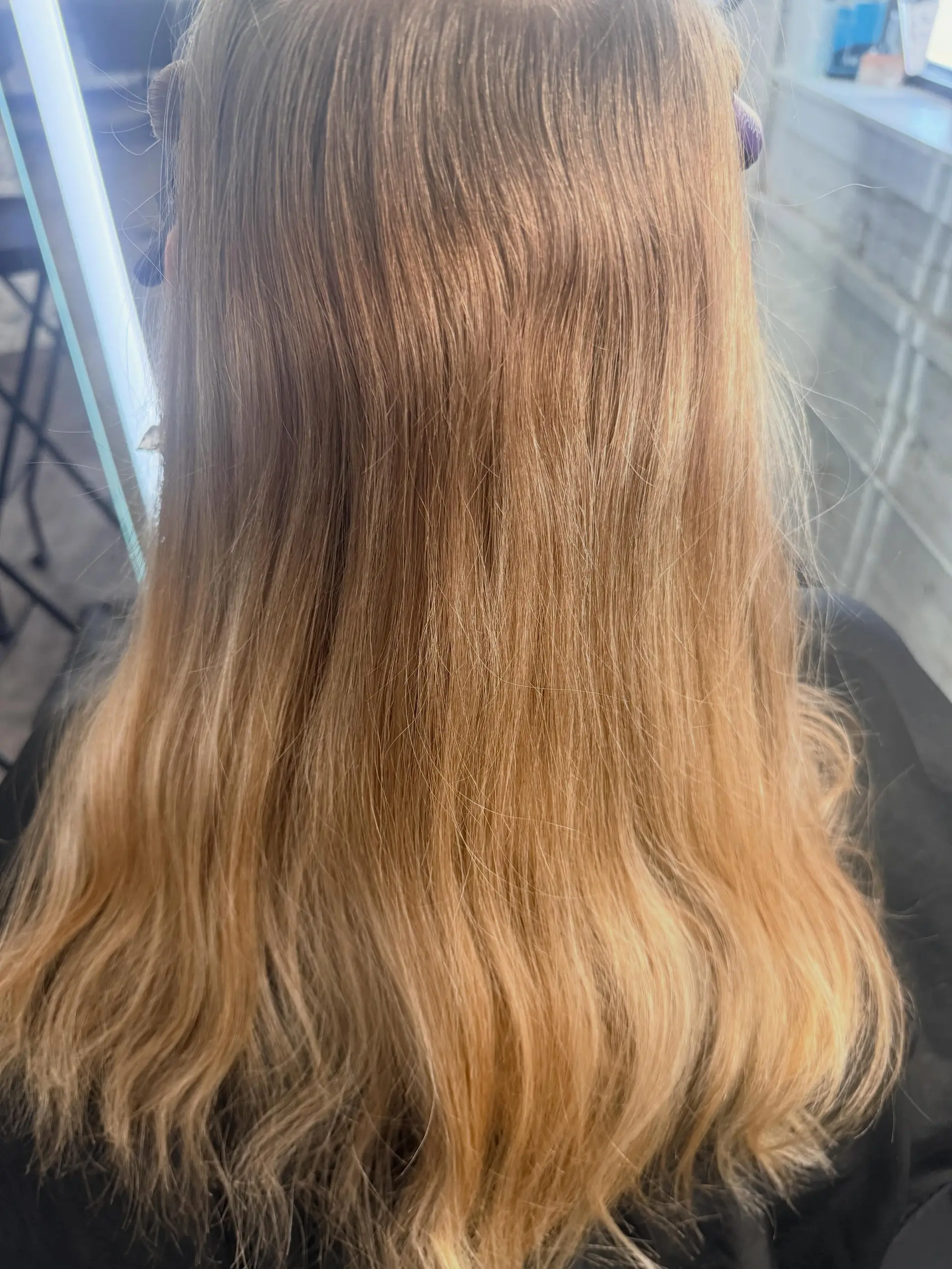 Long warm golden blonde hair styled straight through the mid-lengths with gentle waves at the ends. 1