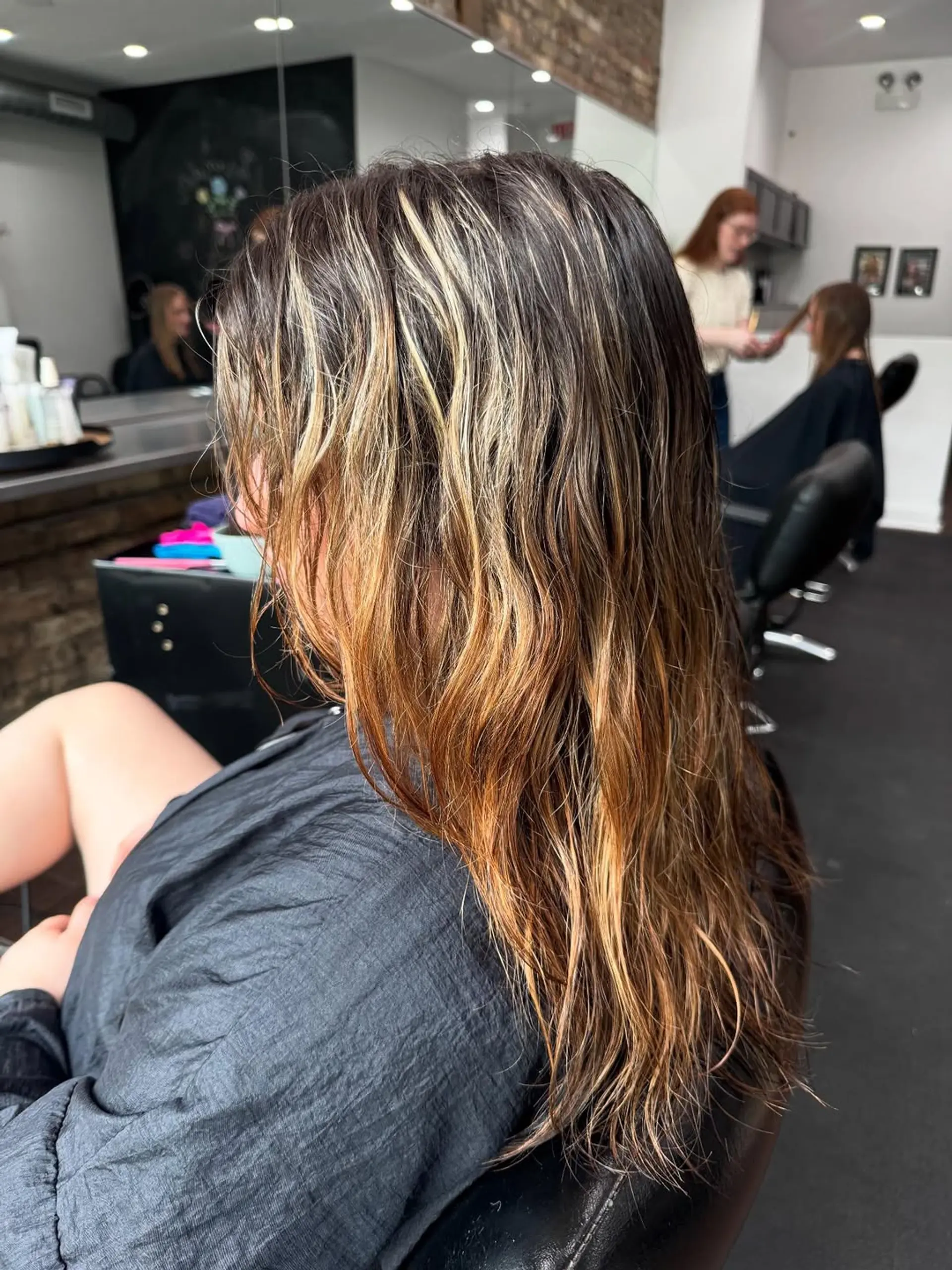 A stylish medium-length haircut featuring voluminous butterfly layers and bold face-framing money piece highlights in vibrant hot pink and peach tones on a dimensional light brown/dirty blonde base. 2