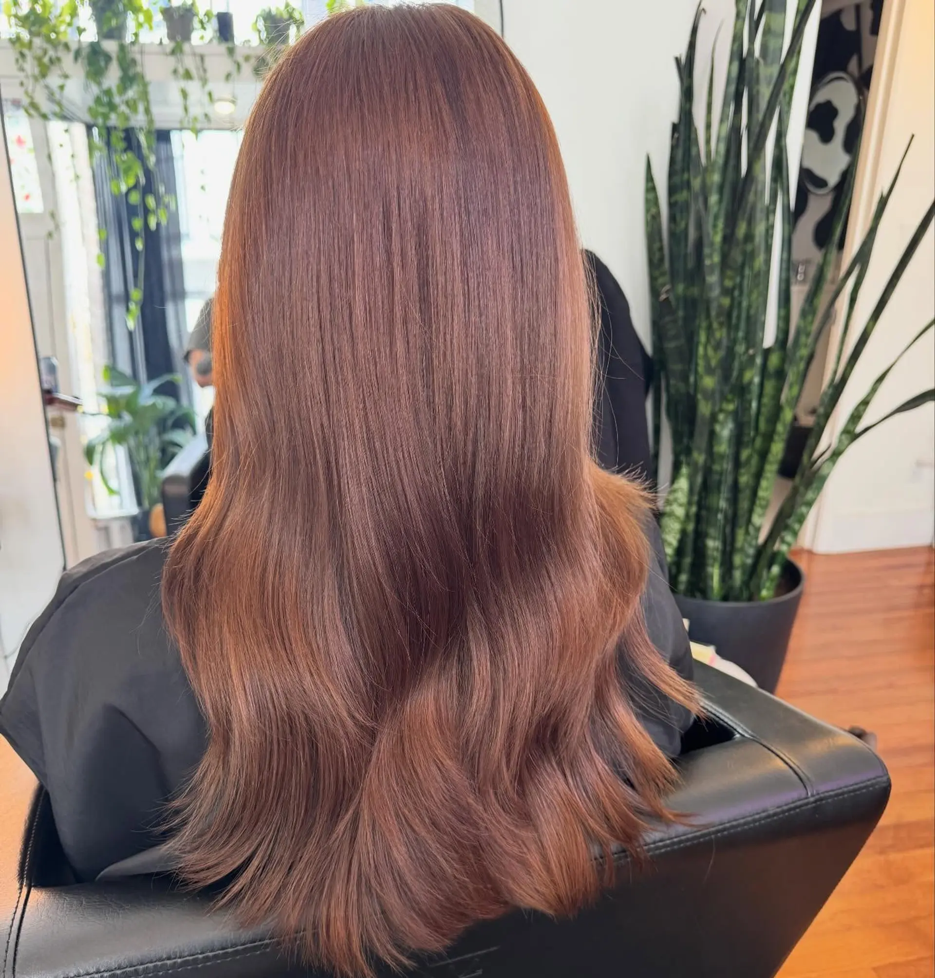 Glossy auburn hair falling mid-back, styled smooth with soft dimensional waves toward the ends. 1