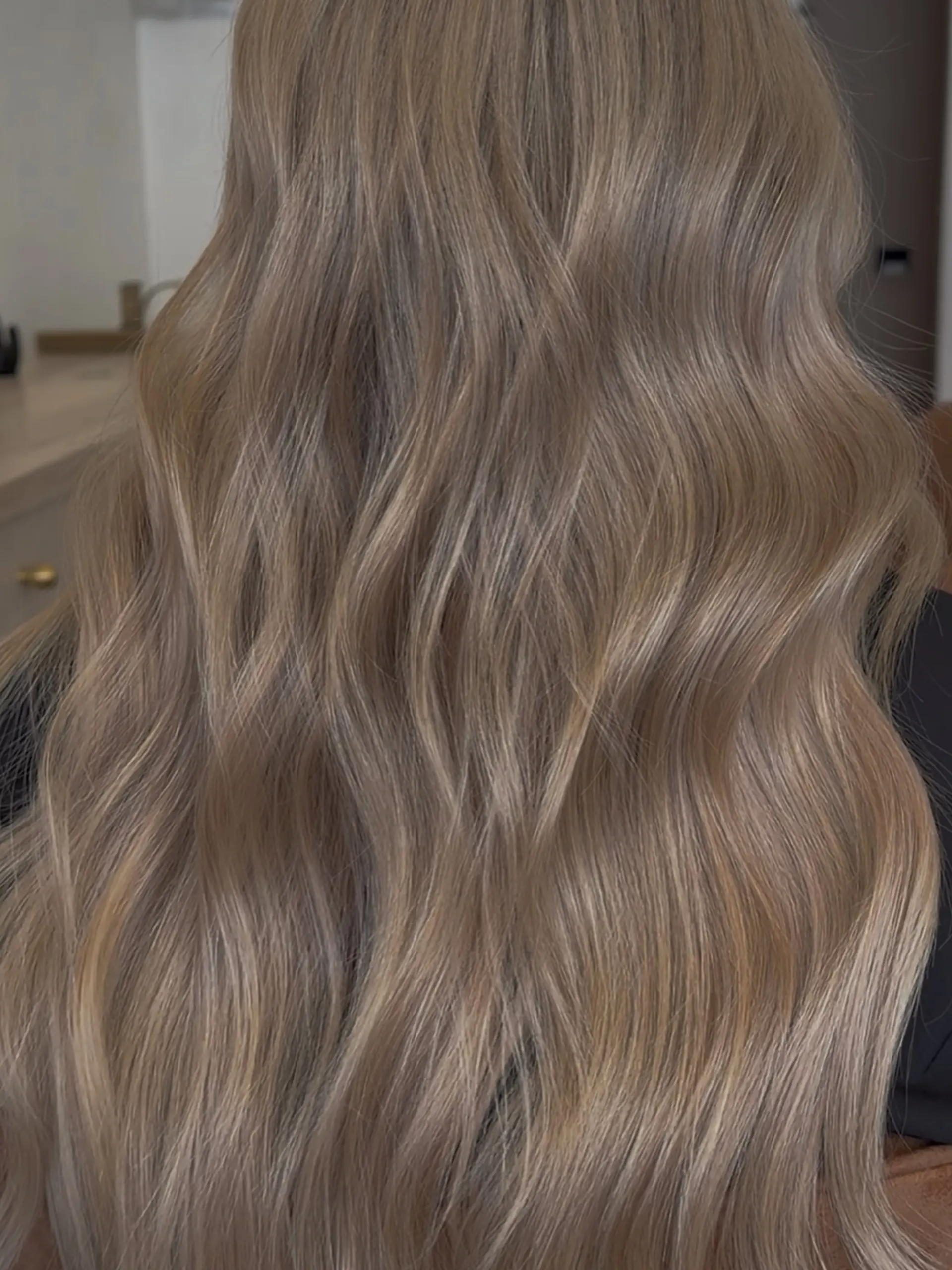 Long, flowing hair styled into soft, elegant waves with cool-toned ash blonde balayage highlights. 1