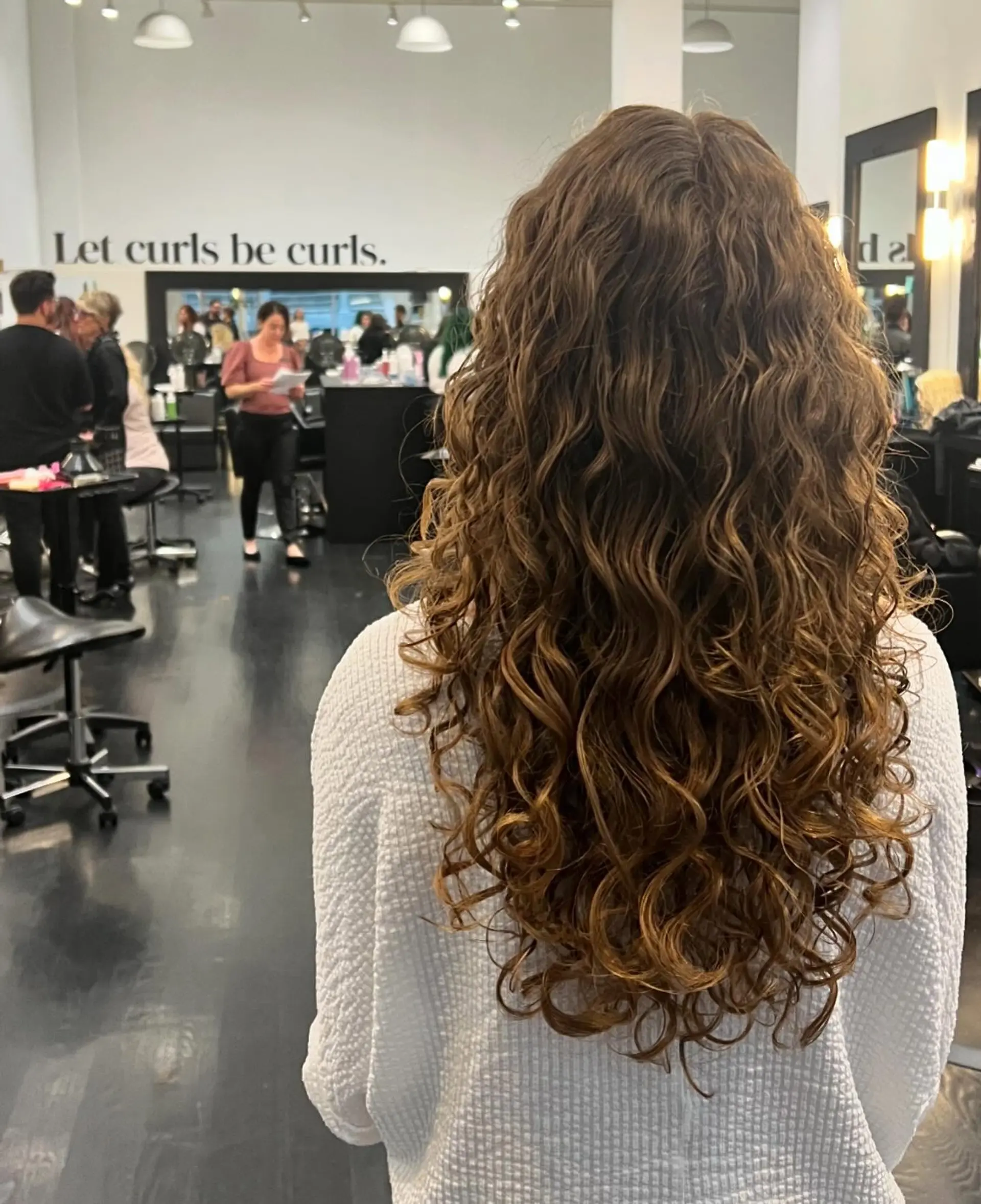 A cascade of long, natural curls with layered shaping that creates soft volume and bounce from roots to ends. 1
