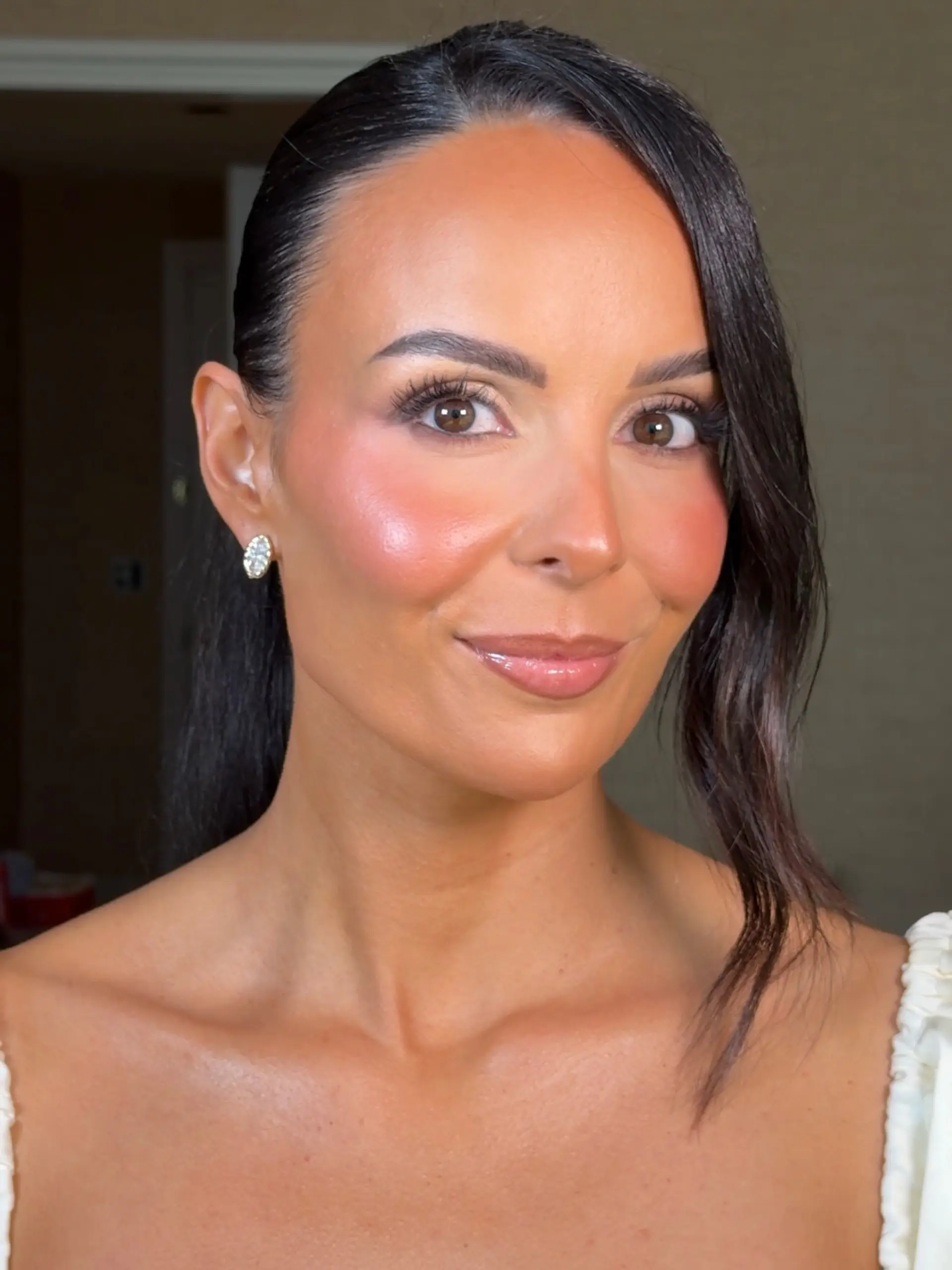 A sleek, side-parted formal style pulled back with a single soft wavy tendril framing the face. 1