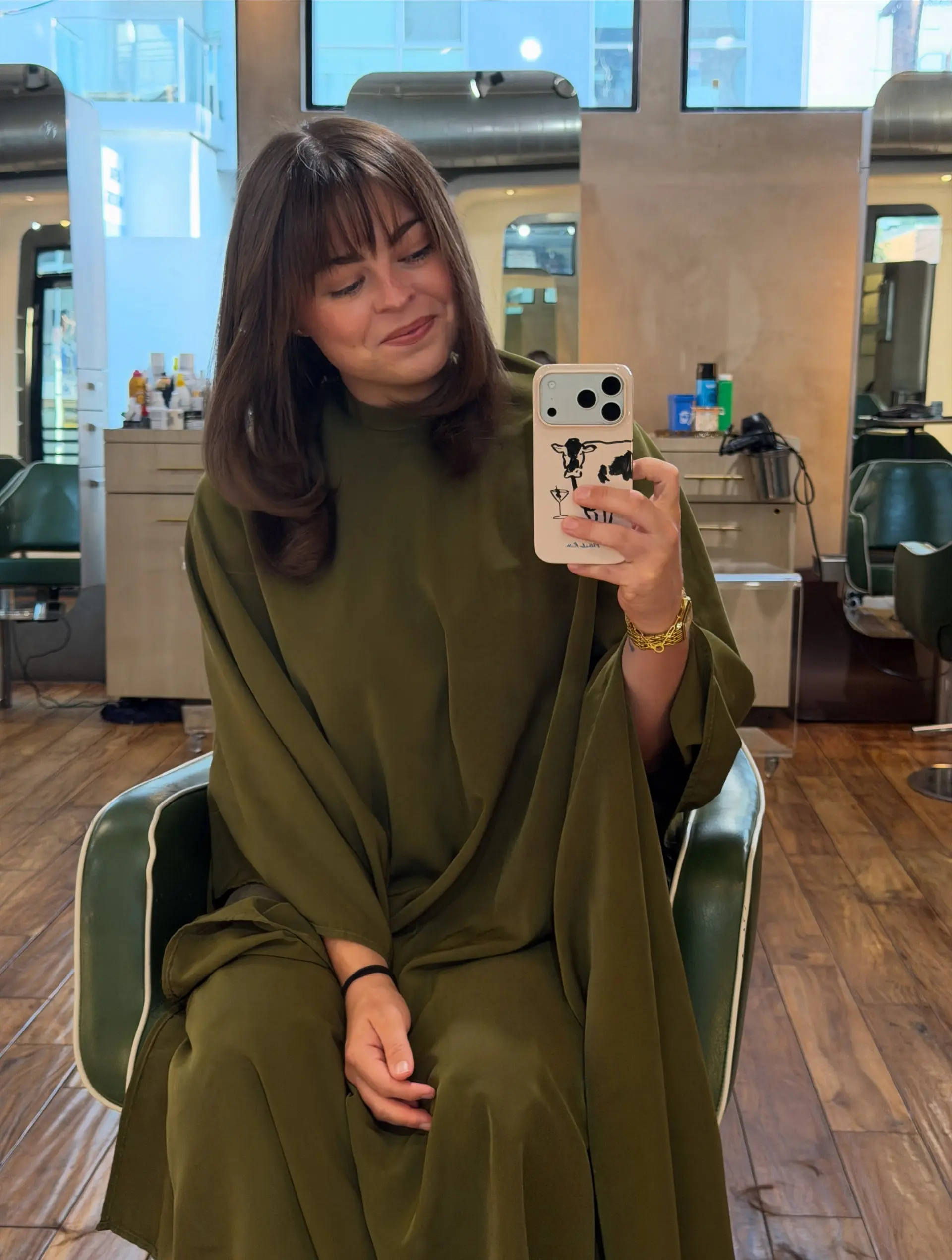 Medium-length brunette hairstyle featuring soft interior layers, smooth blow-dried curved ends, and wispy eyebrow-skimming bangs. 1
