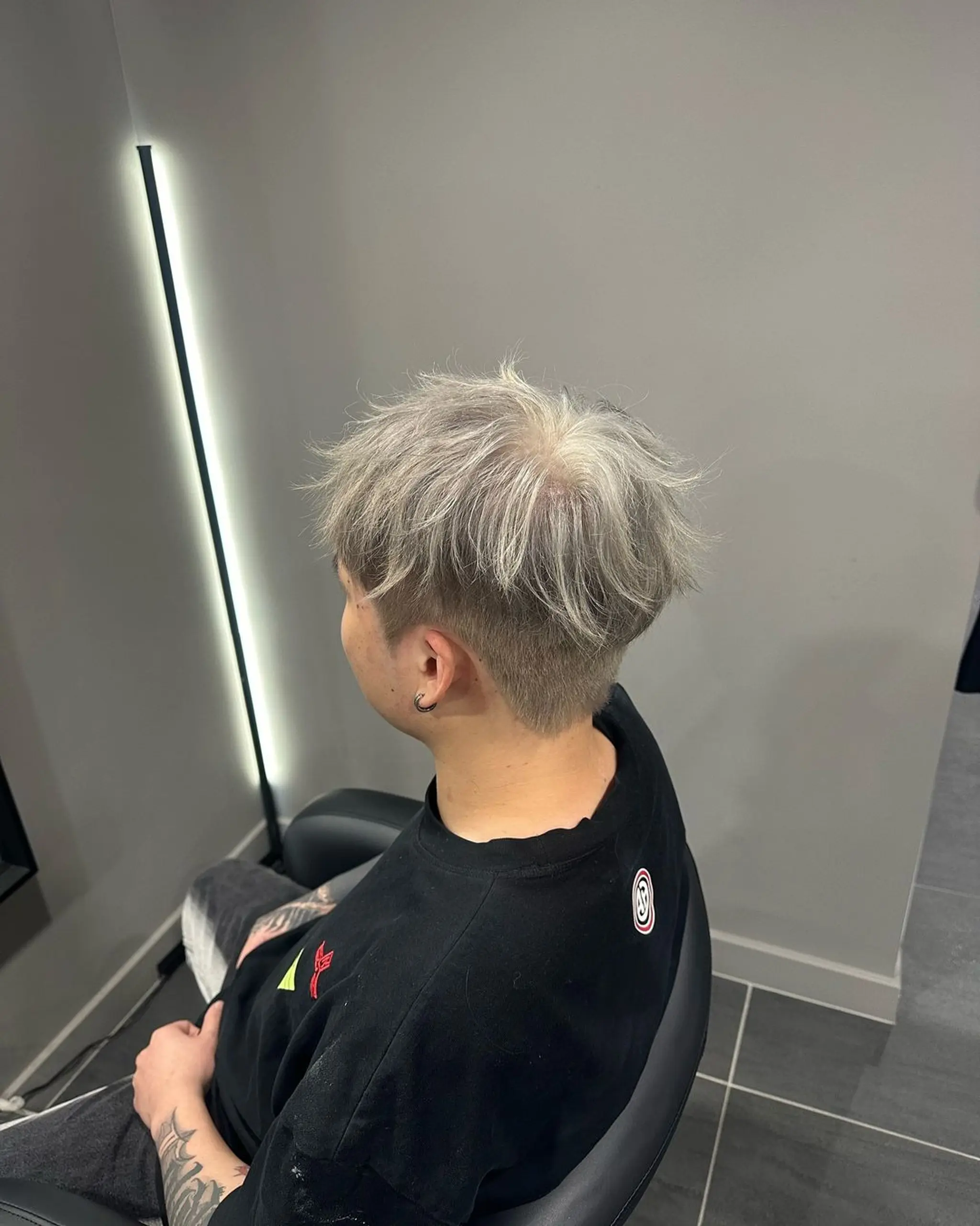 Short, platinum and ash grey hair with a fade undercut and textured, brushed-up top. 2