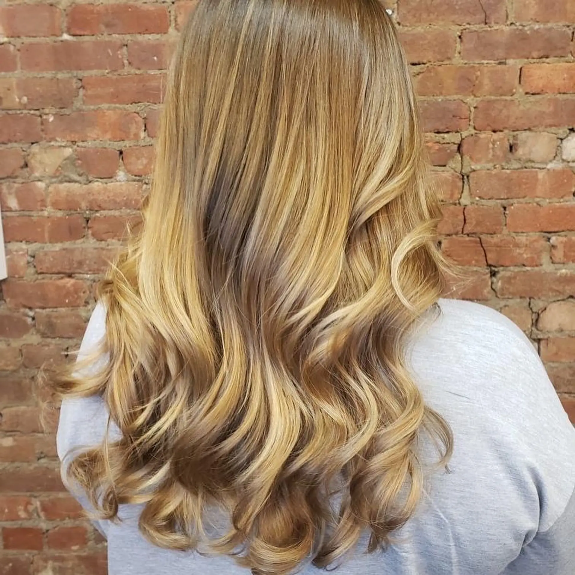 Long hair featuring warm golden blonde balayage highlights styled in soft, bouncy waves at the ends. 1