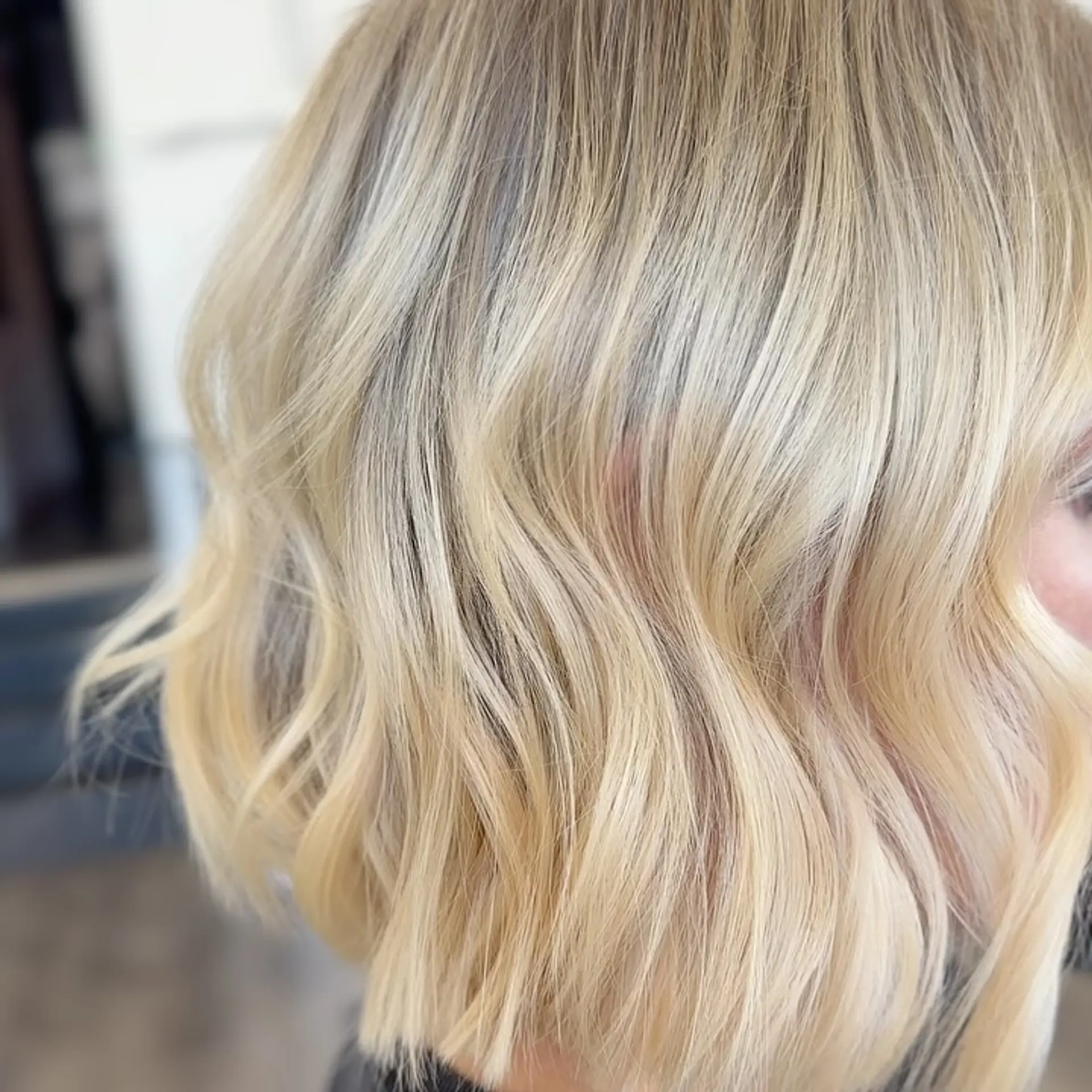 A blunt short bob featuring multi-dimensional lived-in blonde tones styled with soft bends. 1