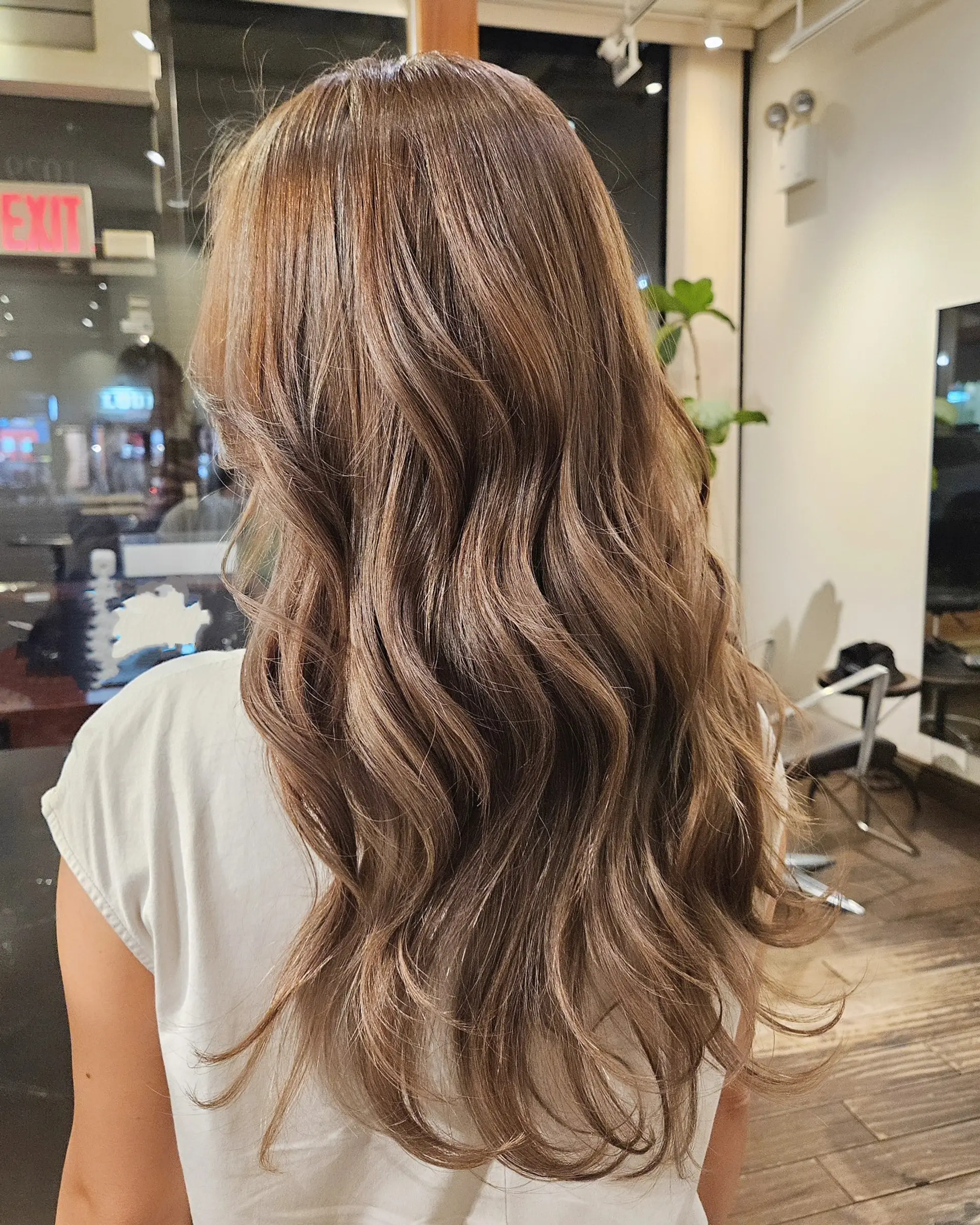 Long layered hair styled in loose, cascading waves featuring soft ash beige highlights throughout a light brown base. 1