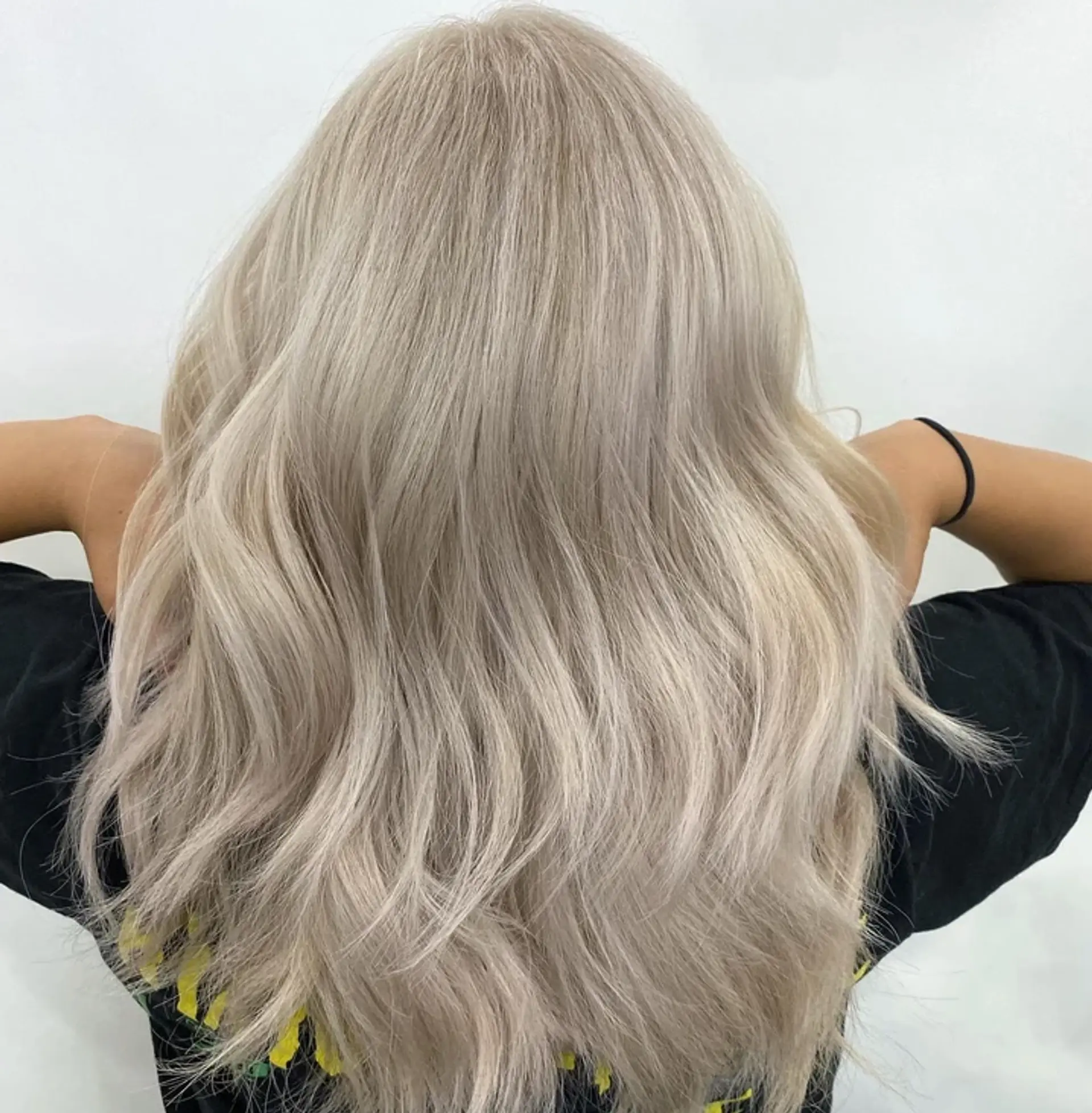 Medium-length, wavy hairstyle with a striking silver and platinum blonde color. Soft waves cascade naturally, giving the hair movement and a voluminous appearance. 1