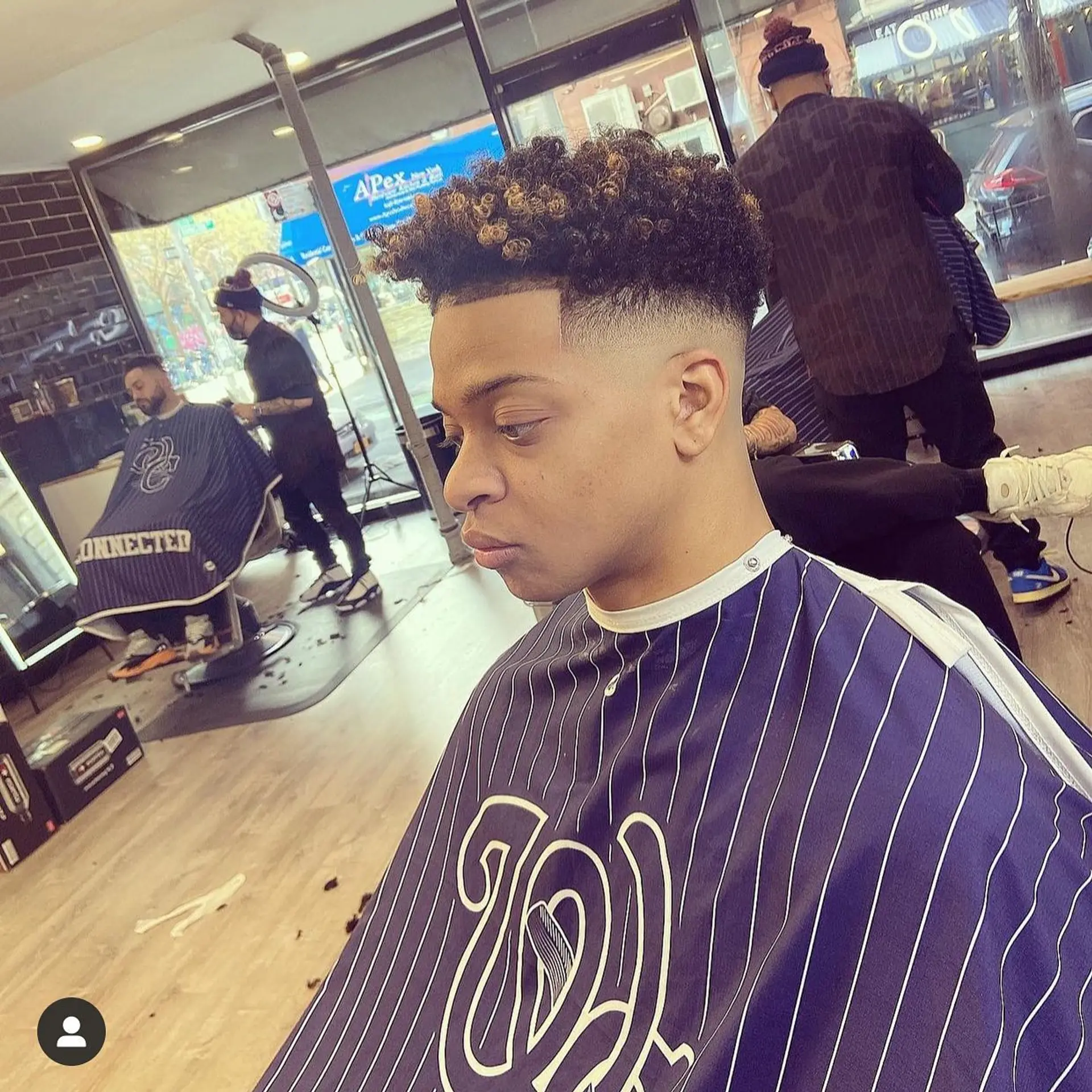 A high skin fade paired with natural curls on top featuring lightened tips and a clean front line up. 1