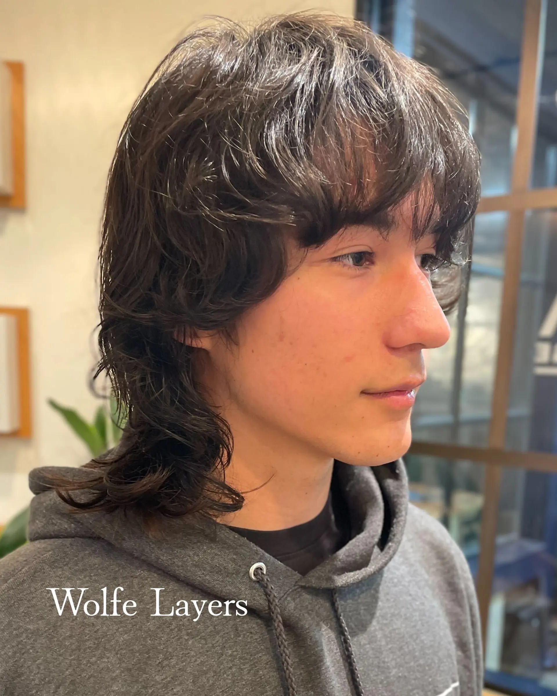 A medium-length wolf cut with shaggy layers, feathered brow-skimming bangs, and natural textured movement tapering down to the neck. 1