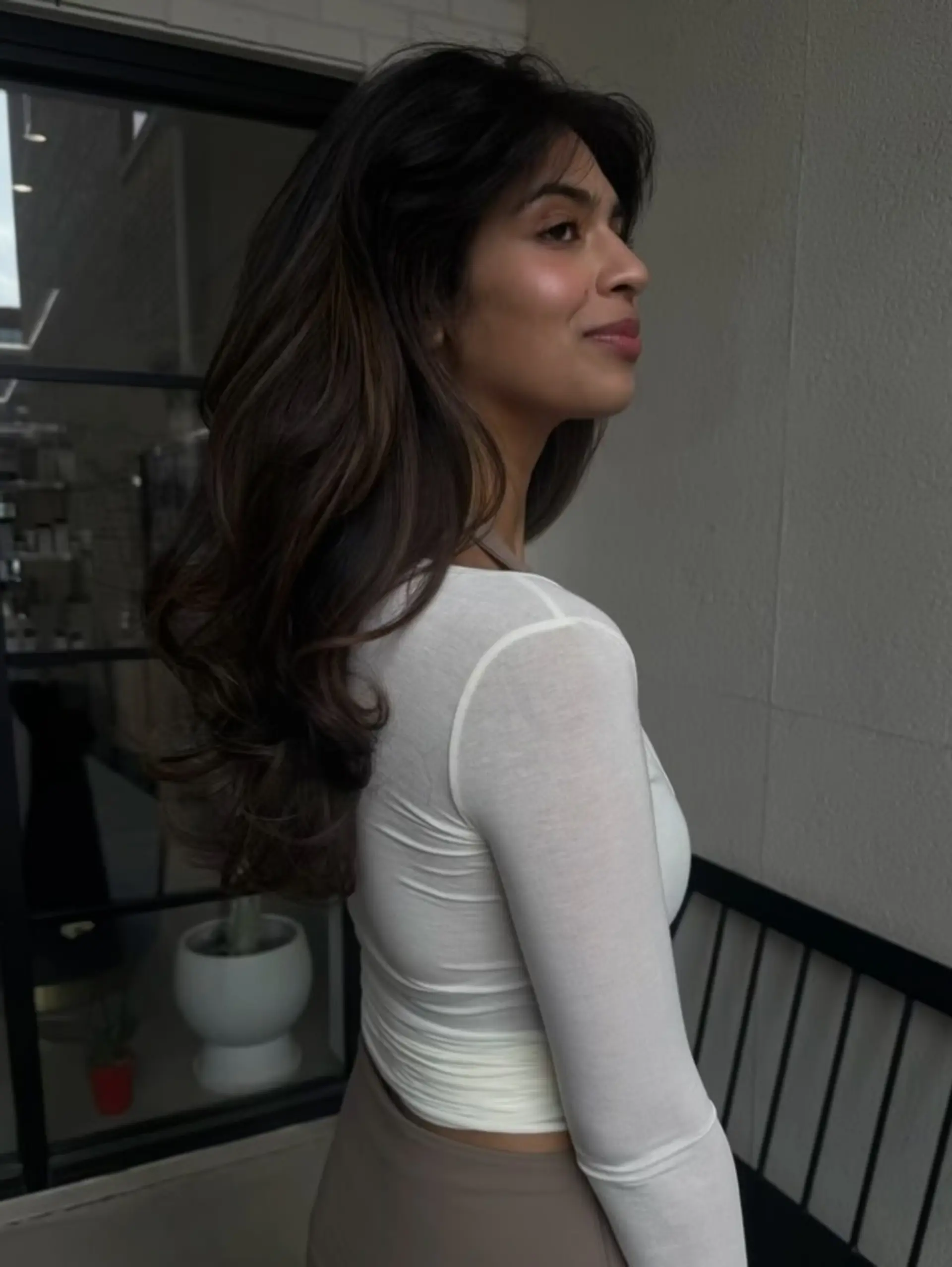 Long, luscious brunette hair styled into a voluminous blowout with soft, bouncy waves and curtain bangs. 1