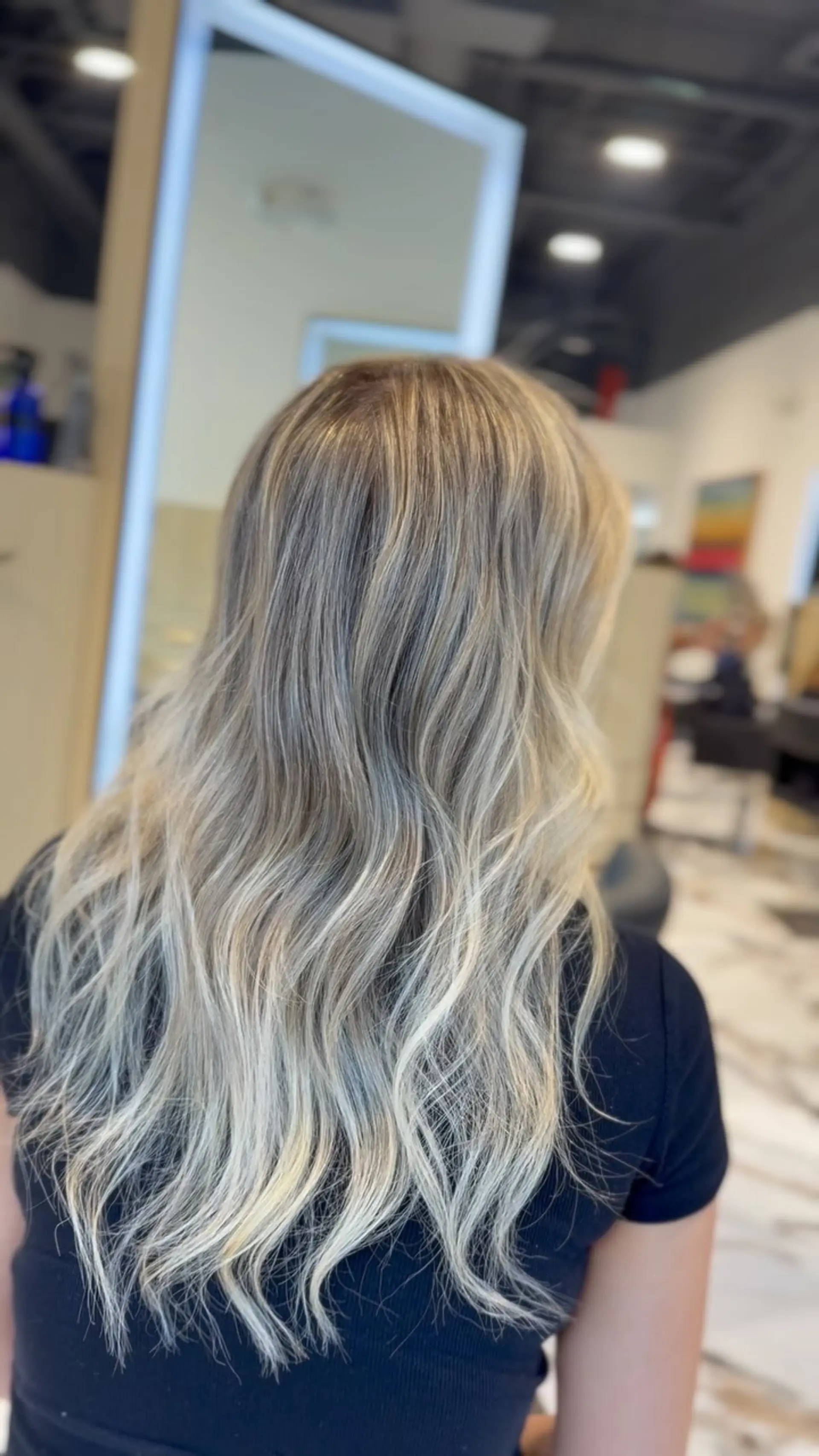 Long ash blonde dimensional hair styled in soft, loose waves cascading down the back. 1