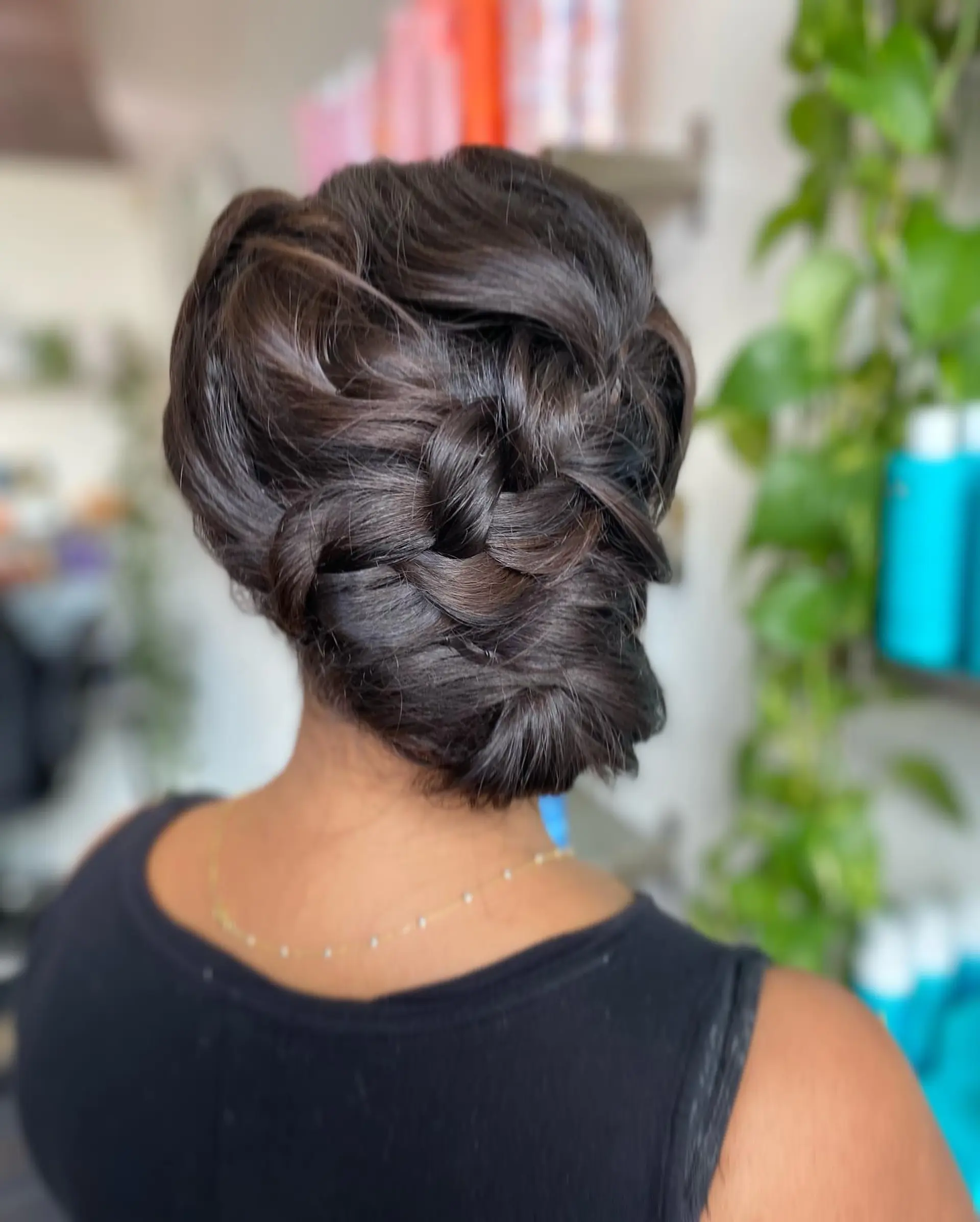 An elegant braided low updo featuring woven sections gathered into a soft, textured chignon at the nape. 1