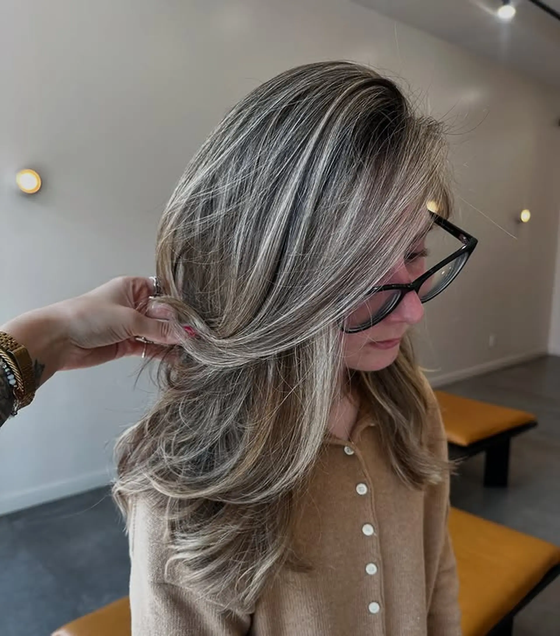 A layered medium length haircut featuring ash blonde balayage with bright money piece highlights. 1