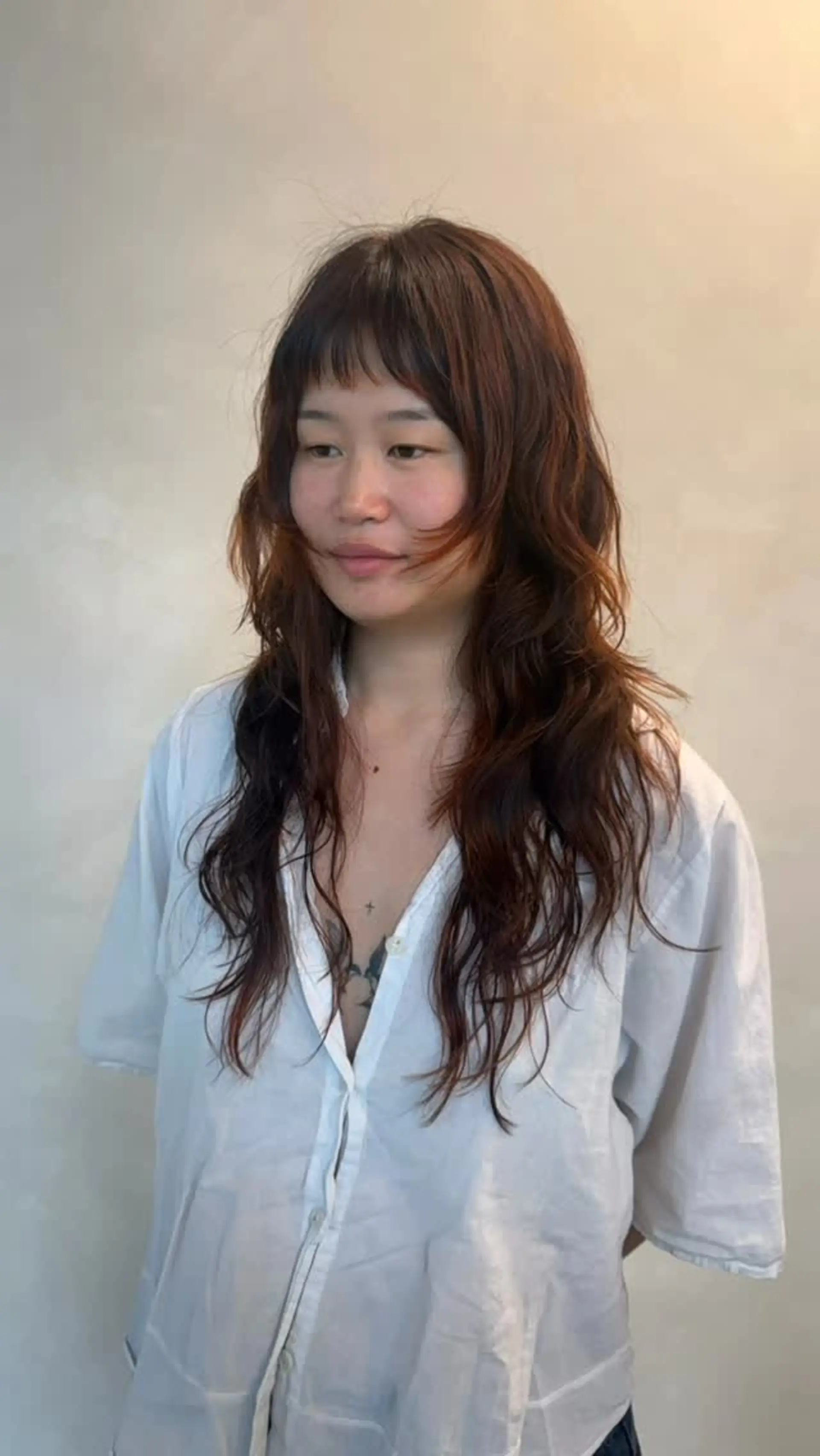 A layered, modern shag haircut featuring textured, soft waves and face-framing fringe with micro bangs, styled in a warm auburn copper tone. 1
