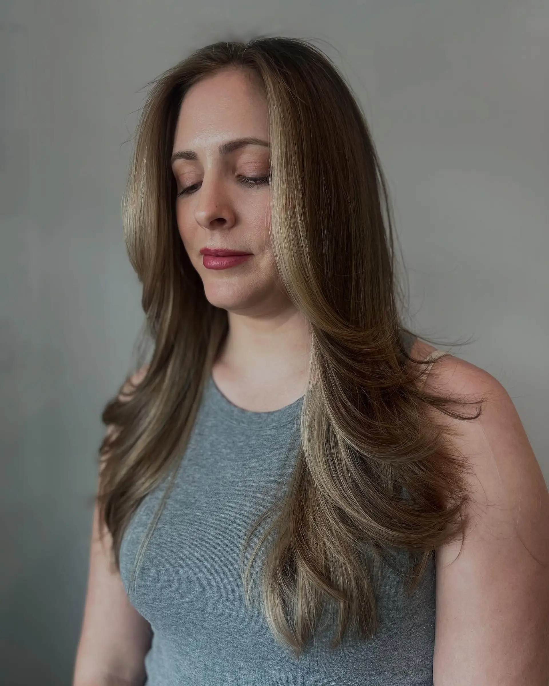 Long layered hairstyle with a bronde color effect and face-framing layers. 1