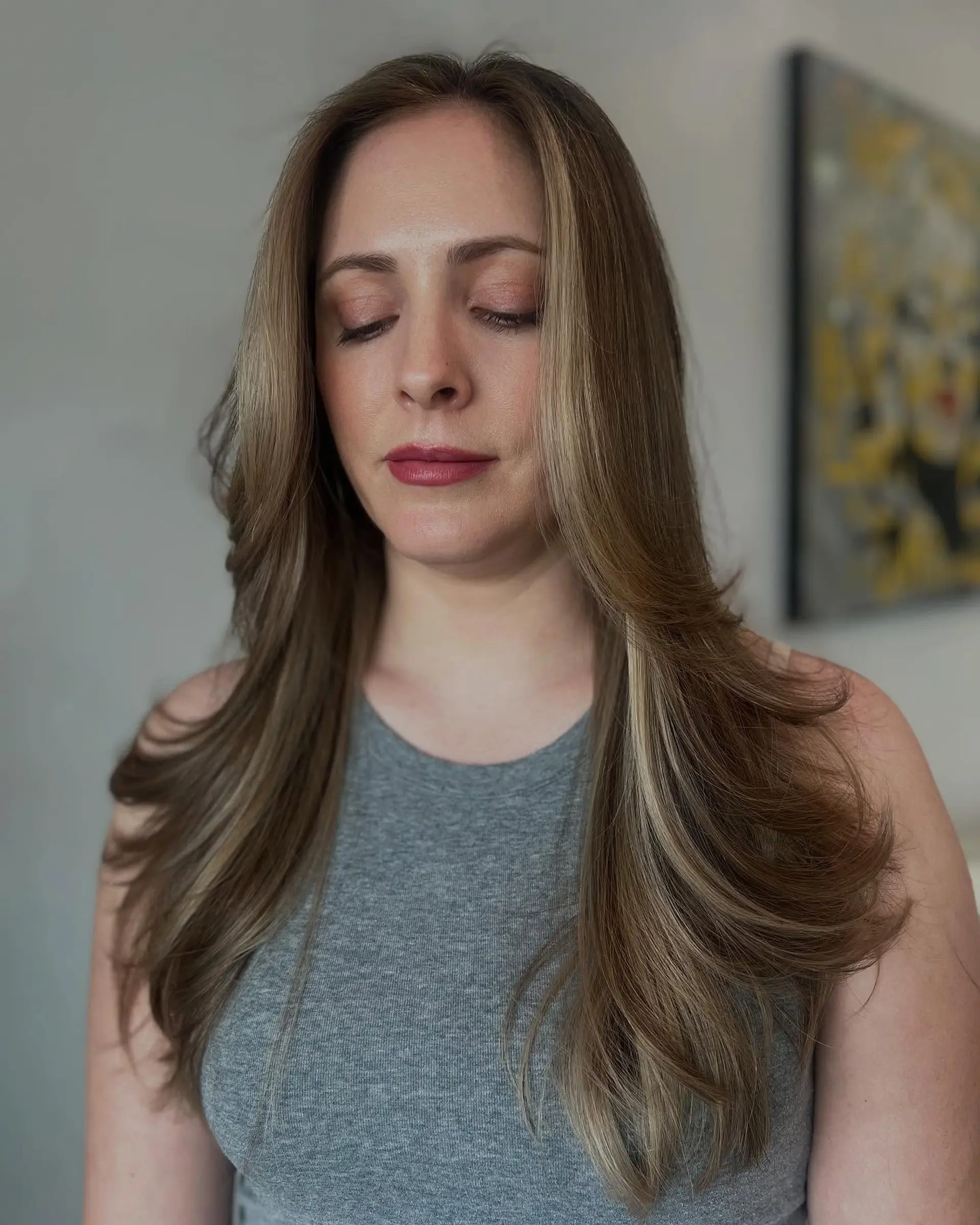 Long layered hairstyle with a bronde color effect and face-framing layers. 2