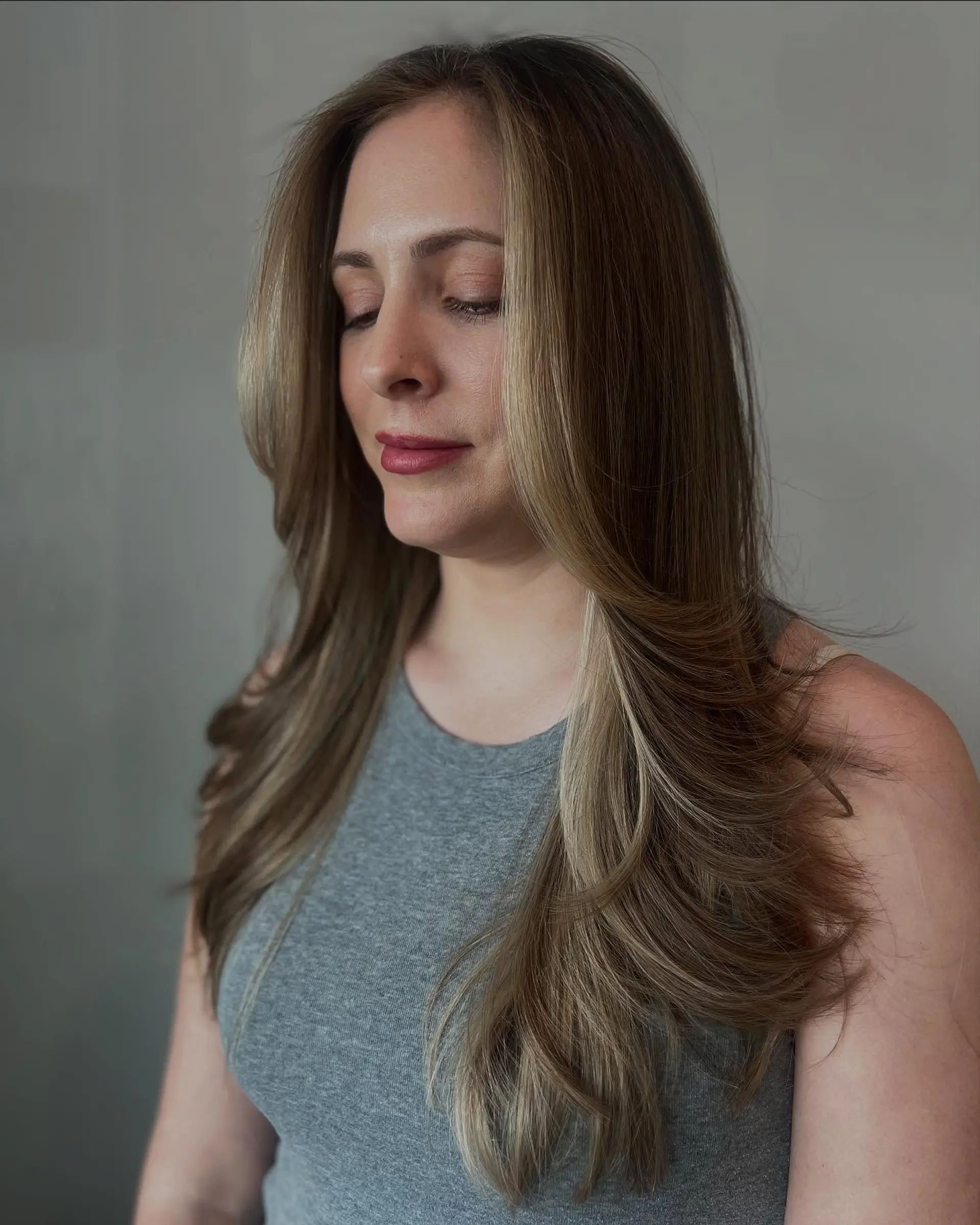 Long layered hairstyle with a bronde color effect and face-framing layers. 3