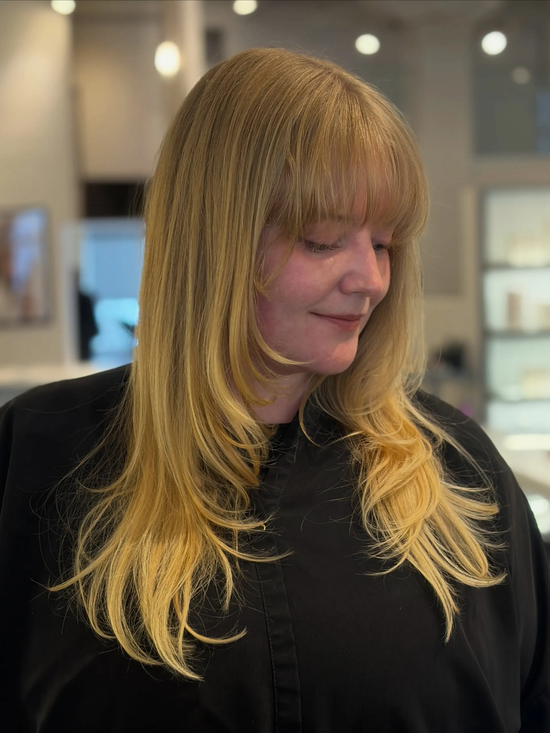 Long golden blonde hair with soft face-framing layers and a full straight across fringe bang. 1