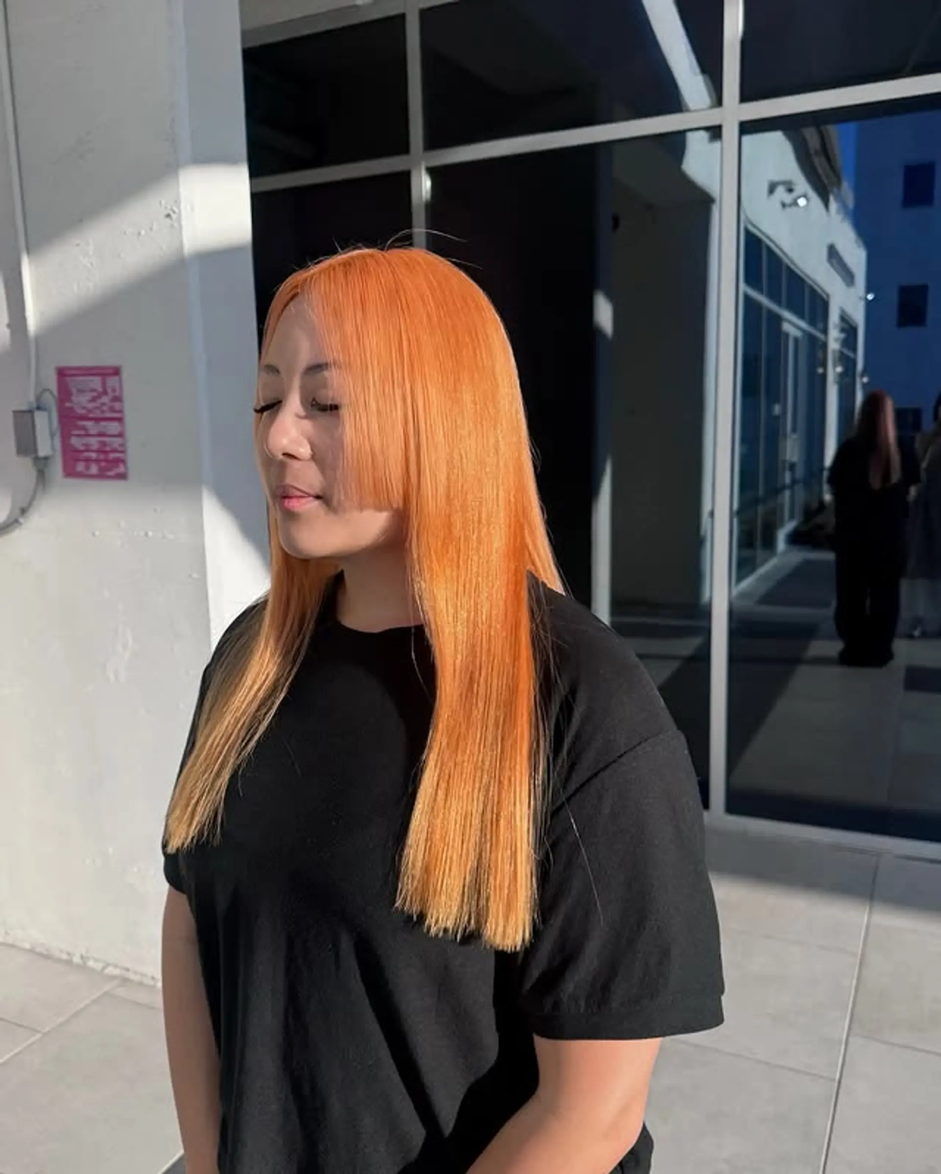 A striking blunt bob with a bold, straight-across fringe, colored in a vibrant tangerine. 1