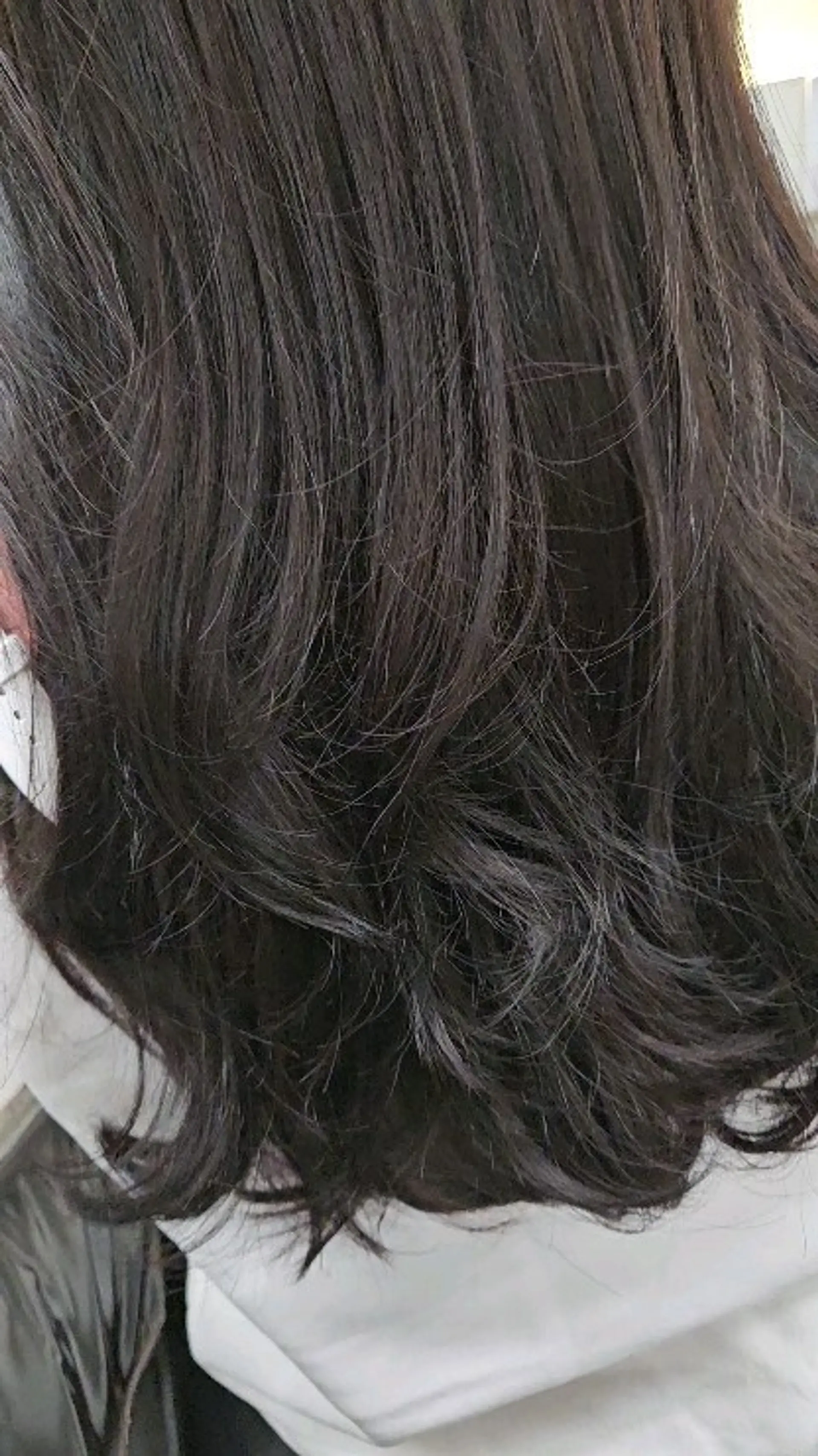 A textured, medium-length haircut featuring flowing layers styled into soft, natural waves with curled ends. 1