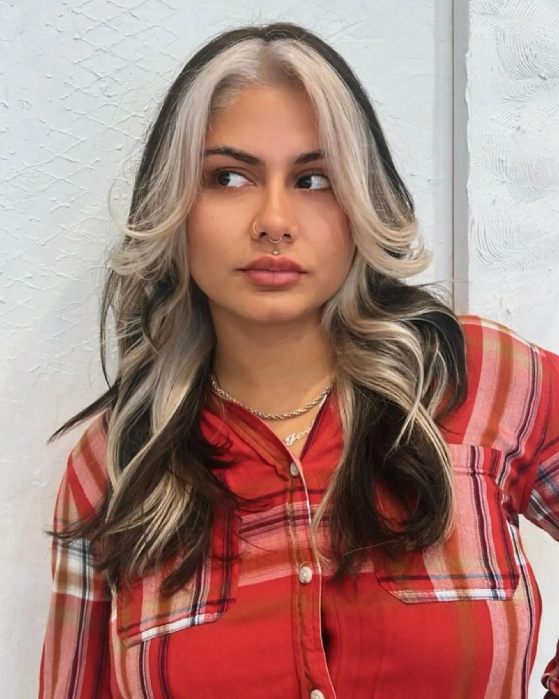 Long, wavy hairstyle with black base color and platinum blonde highlights, featuring a center part and face-framing layers for added volume and dimension. 1